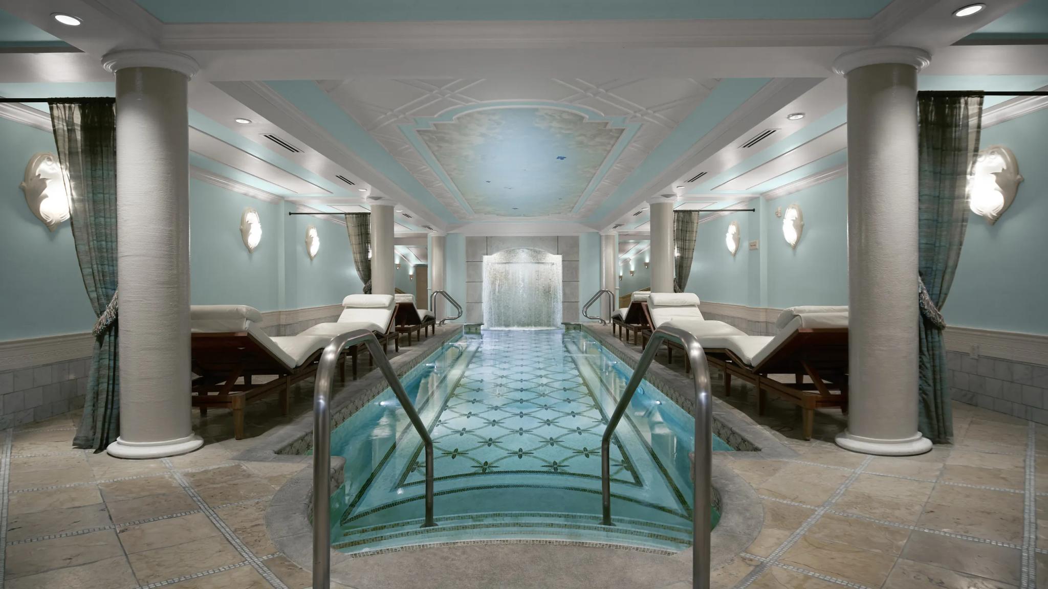 Panoramic view of a indoor swimming pool surrounded by sunbeds