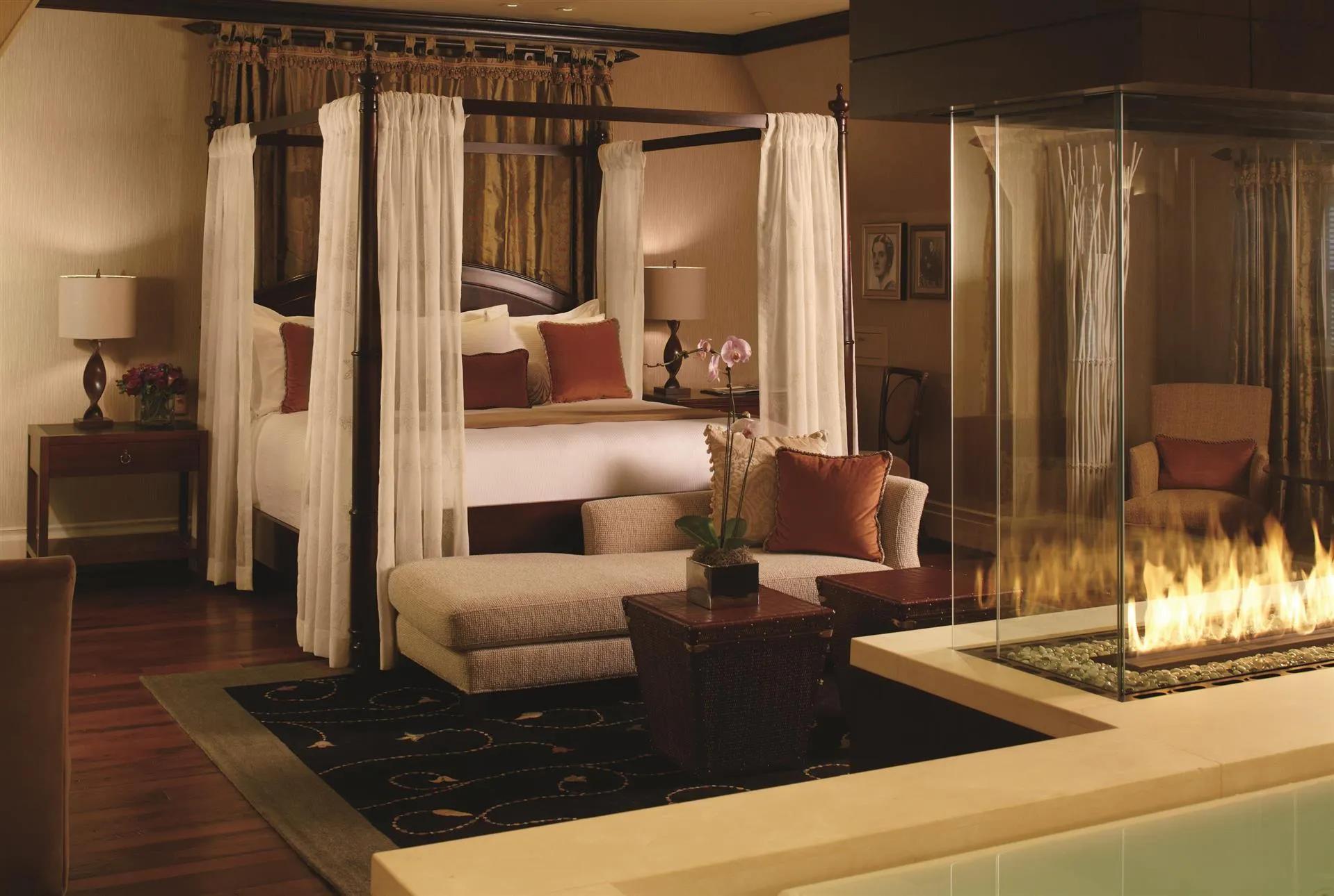 A grand double bed room surrounded by curtains with a fire pit in the room