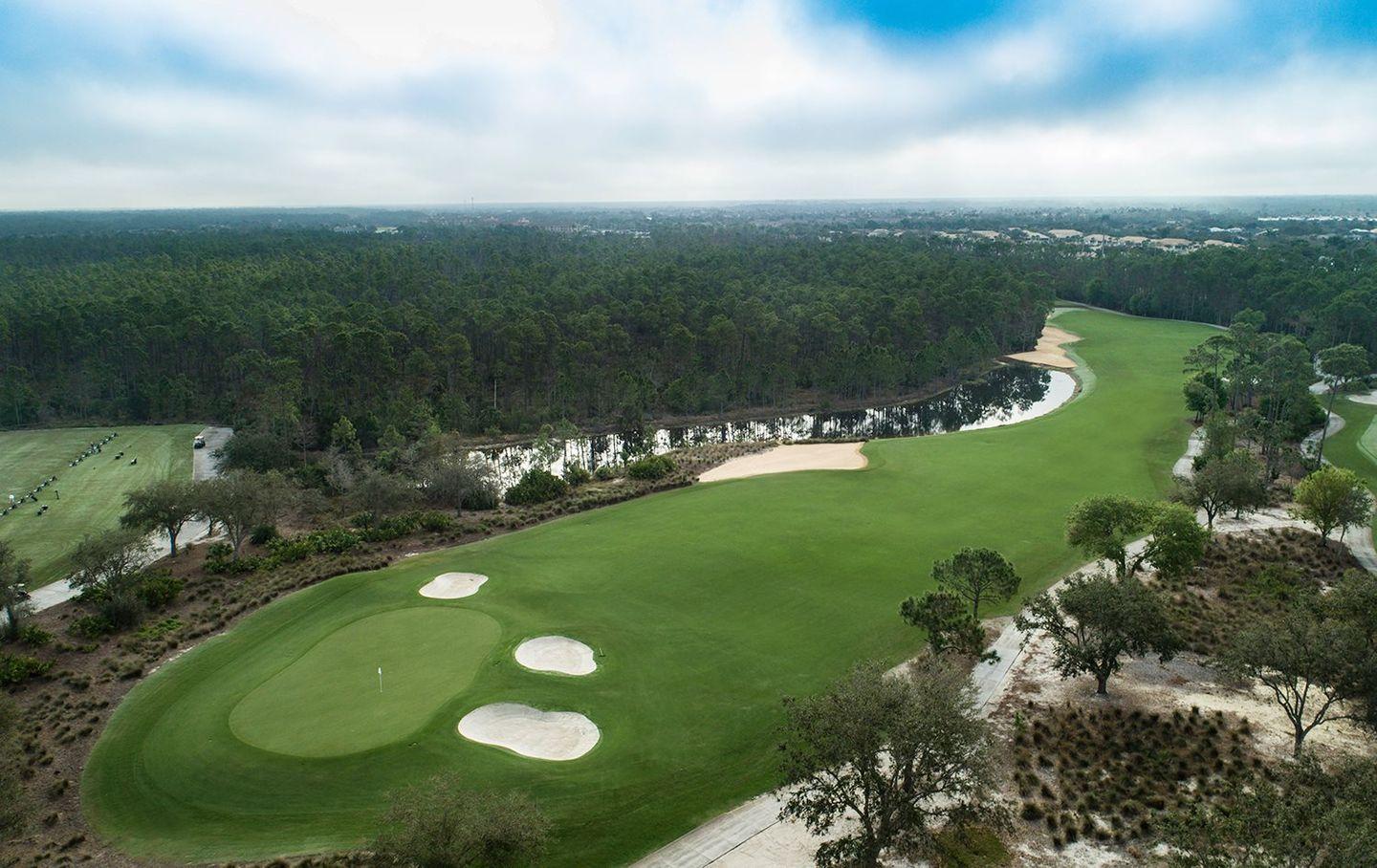 A wide fairway bordered by sand bunkers and dense forest in the distance.