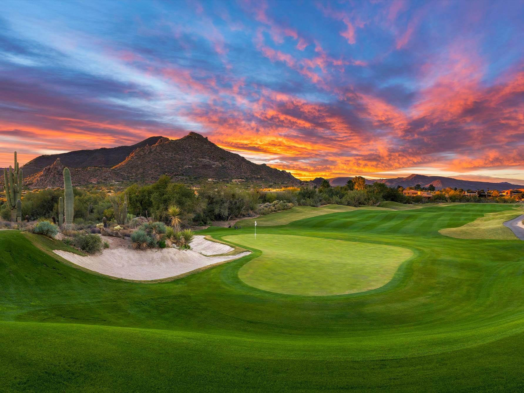 Sun setting over the North Course with wide fairways and a well-maintained green with a mountain in the distance
