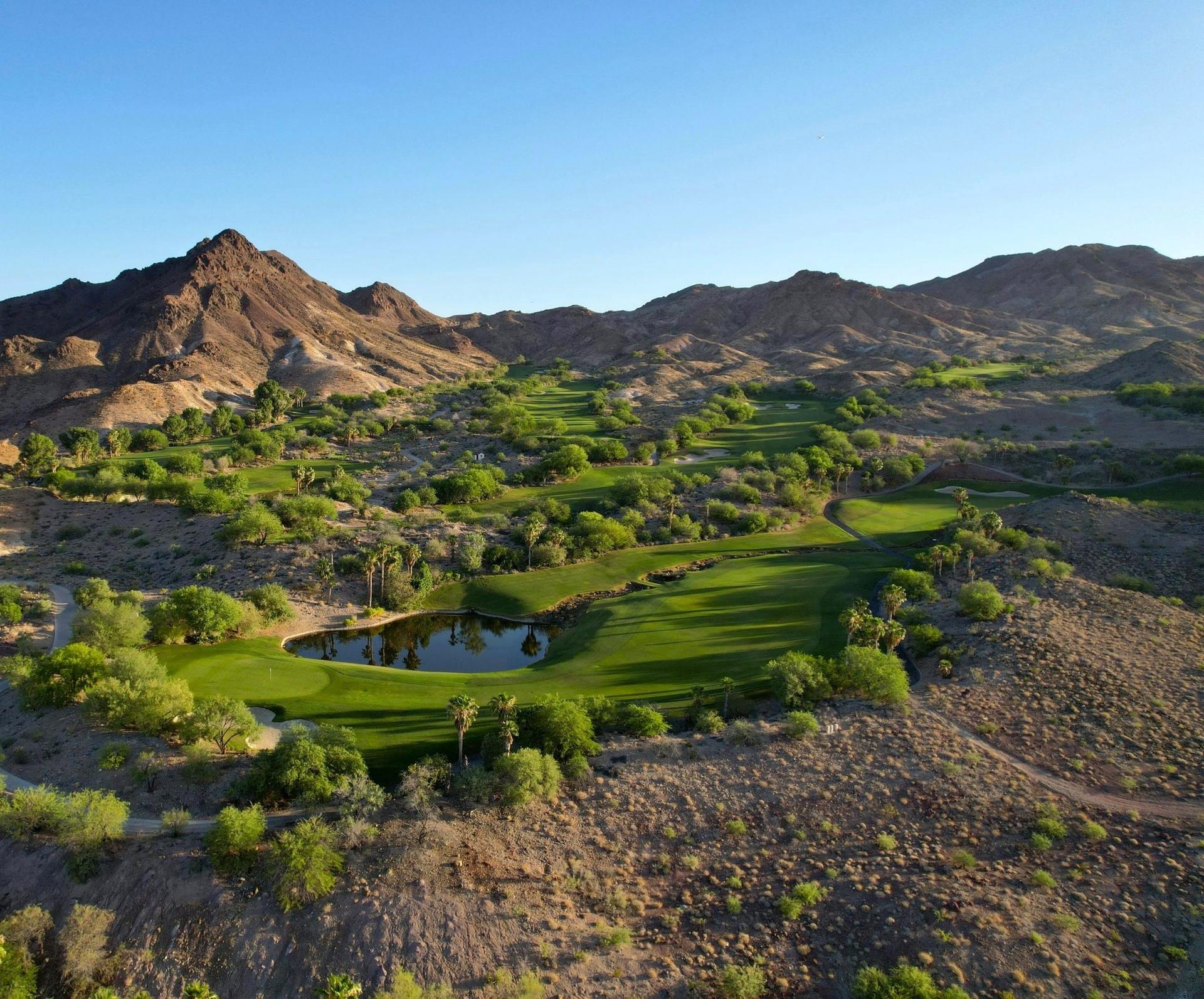 Green fairways winding through rocky desert terrain with scenic mountain views.