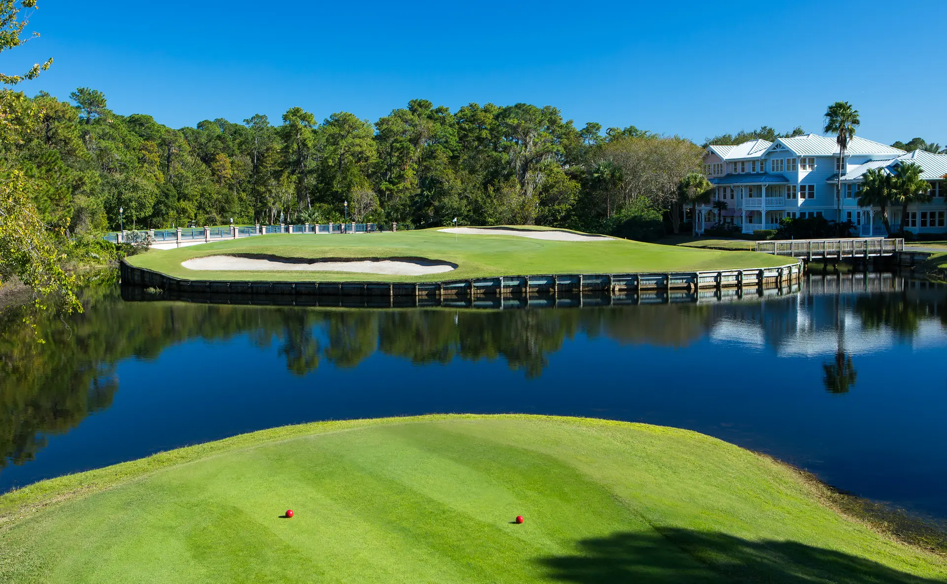 Water hazard surrounding an elevated green with a bridge to navigate the course