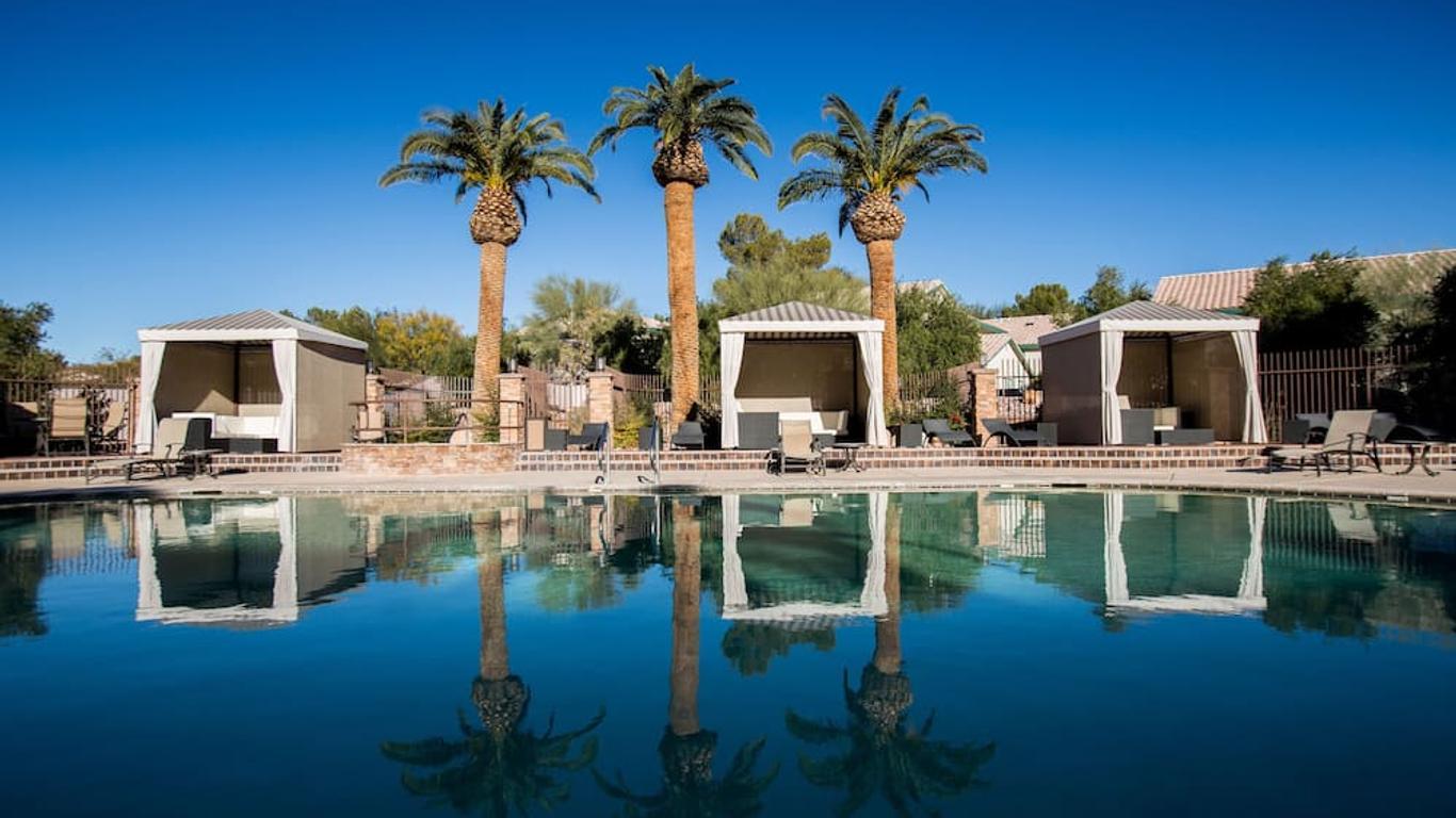 Outdoor swimming pool reflecting the surrounding cabanas and palm trees