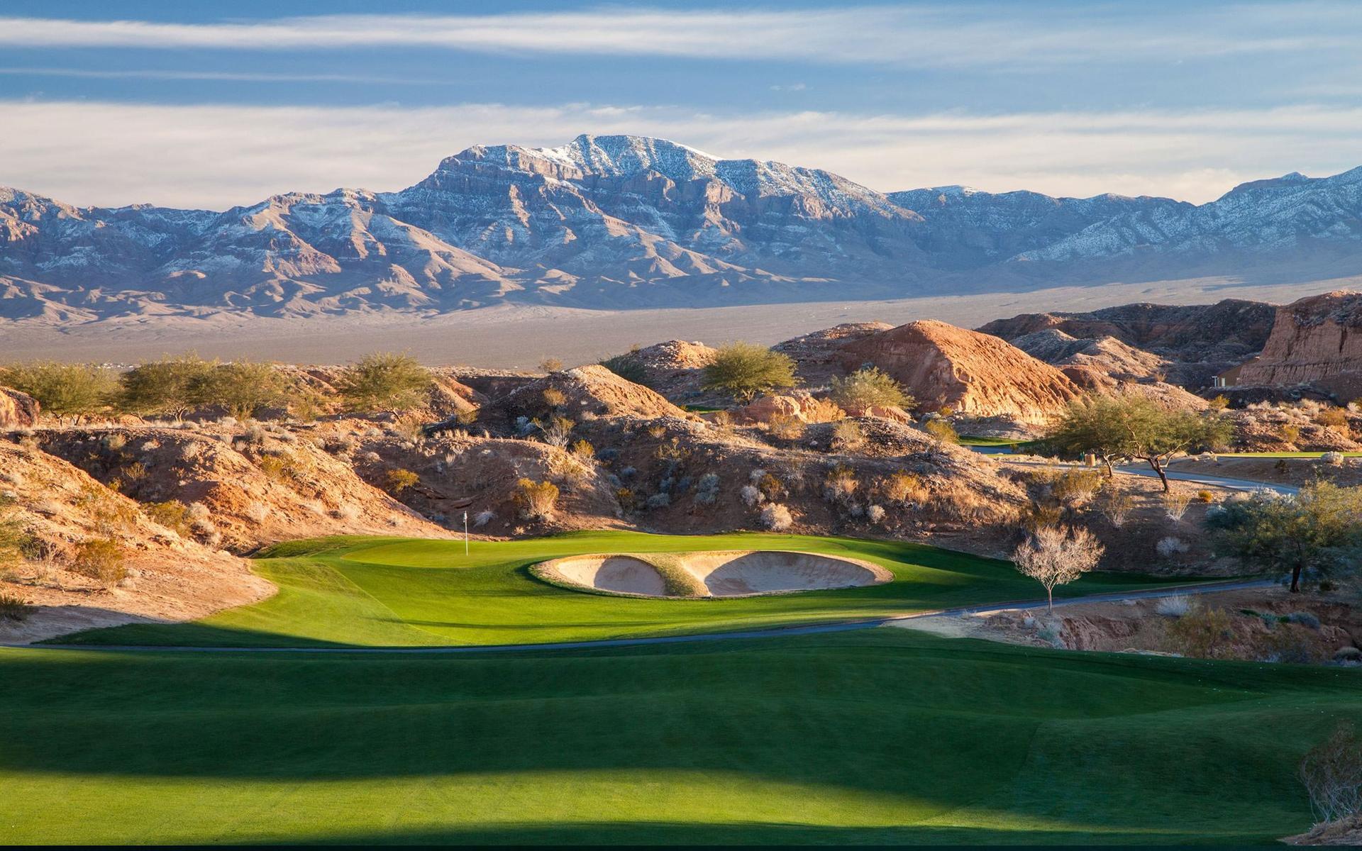Manicured fairway nestled with sand bunkers with stone mountains in the distance