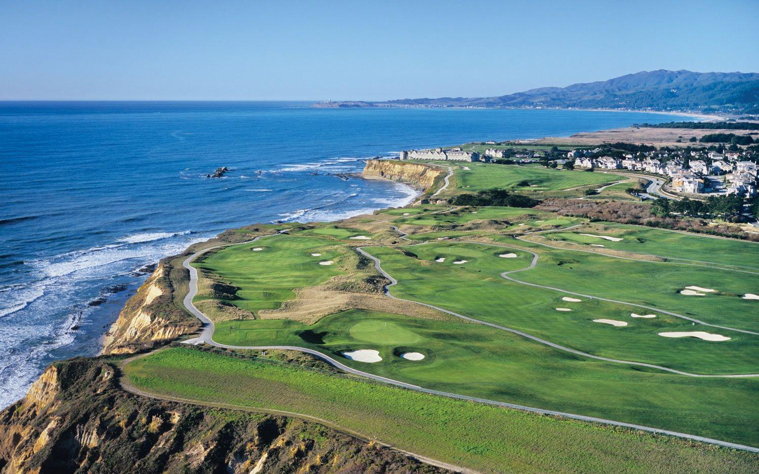 Aerial view of the course littered with sand bunkers and coastal views