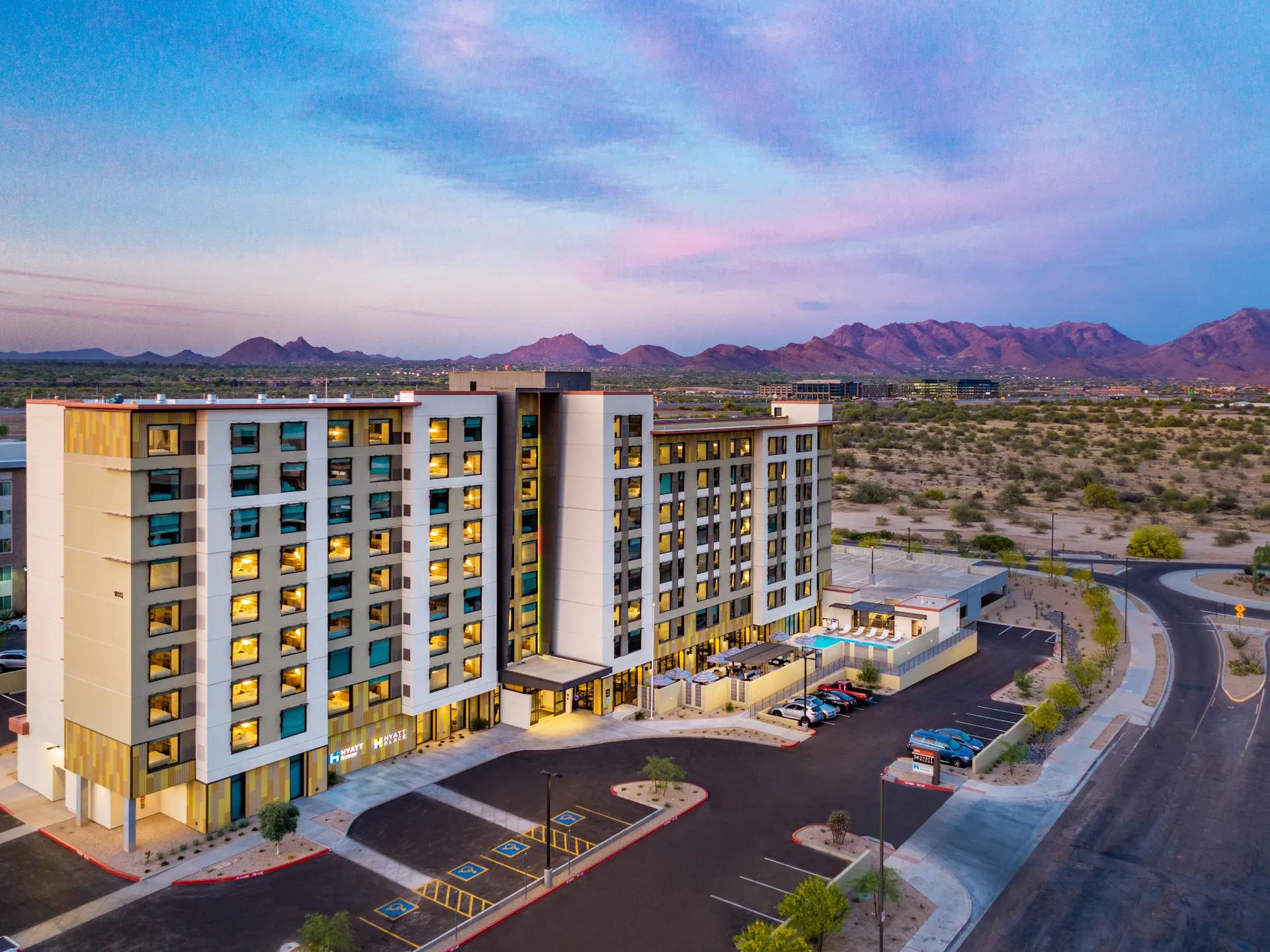 Exterior birds eye view of the Hyatt House under purple skies with mountains in the distance