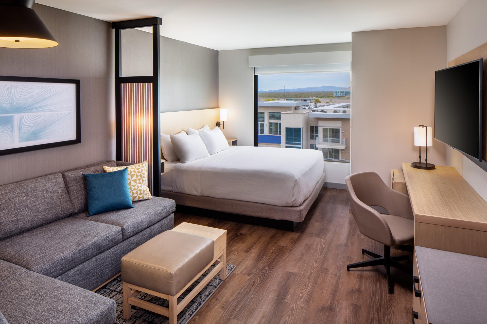 Double bed suite with a sofa area, smart TV and window views of the city