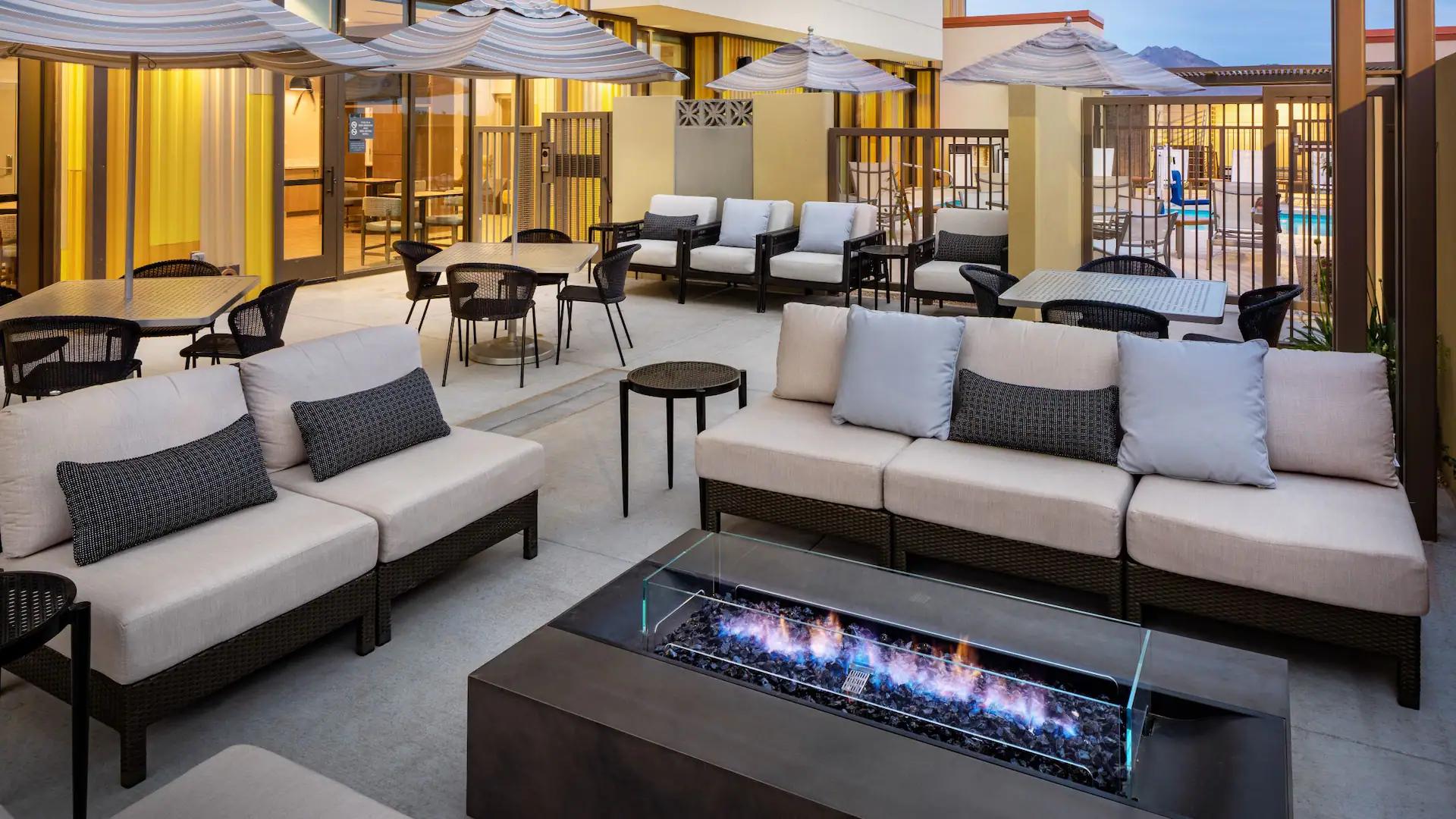 Fire pit places in the centre of an outdoor seating area with tables and sofas available