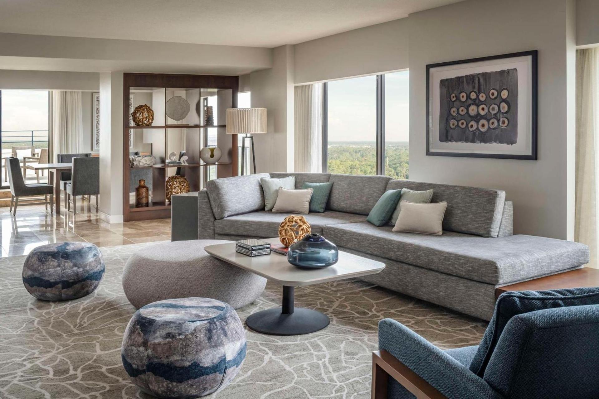 Modern sitting & dining room at the Hyatt Regency Grand Cypress featuring a large sofa, panoramic windows and a balcony