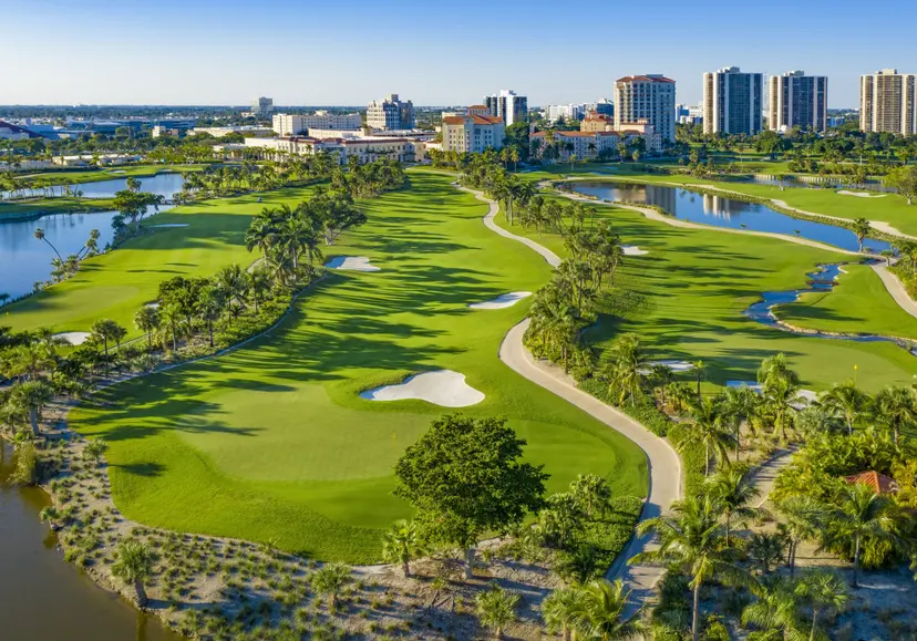 Panoramic aerial view of the course surrounded by palm trees and sand bunkers under clear blue skies