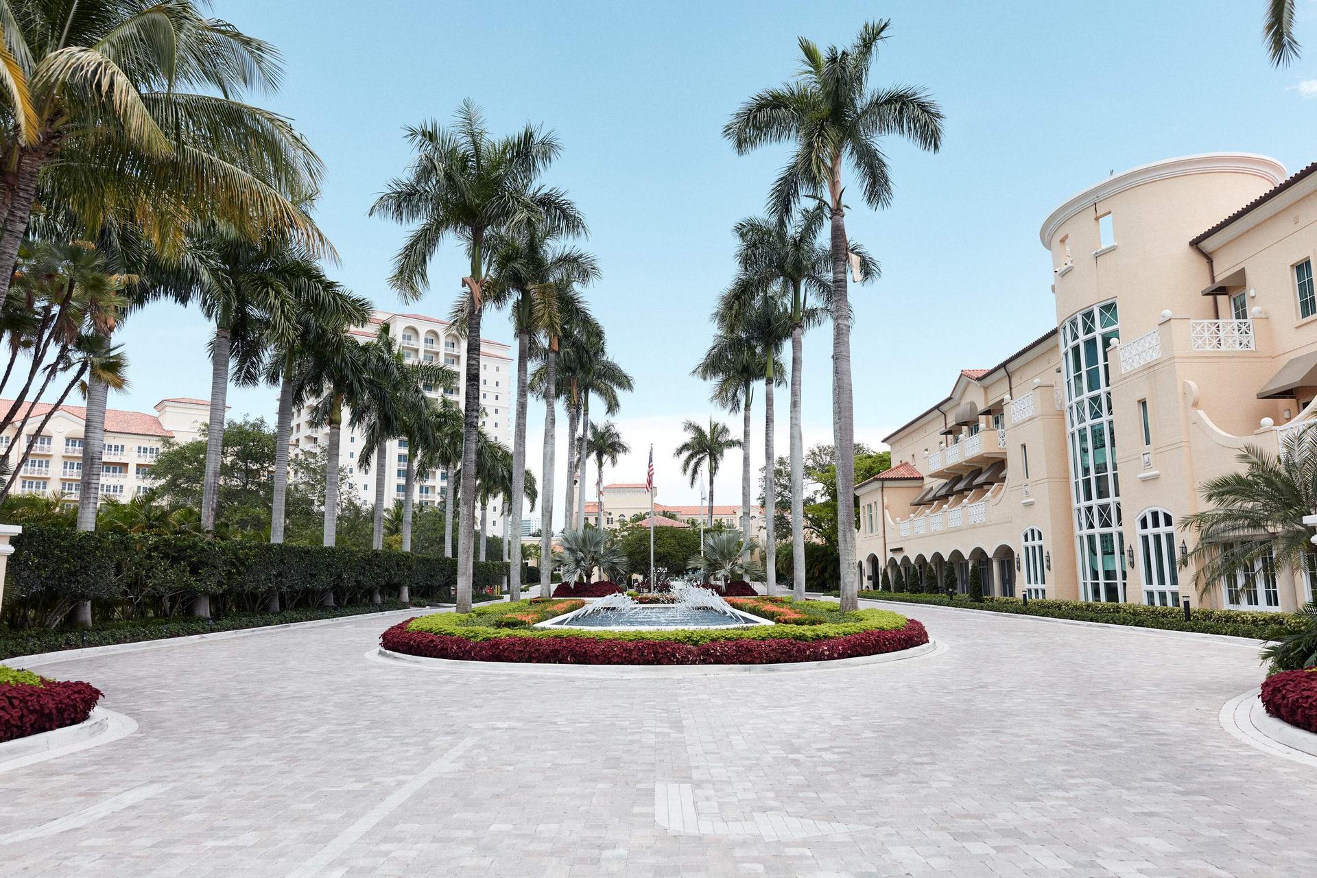 Grand front entrance at the resort with a water feature being surrounded by palm trees and flowers