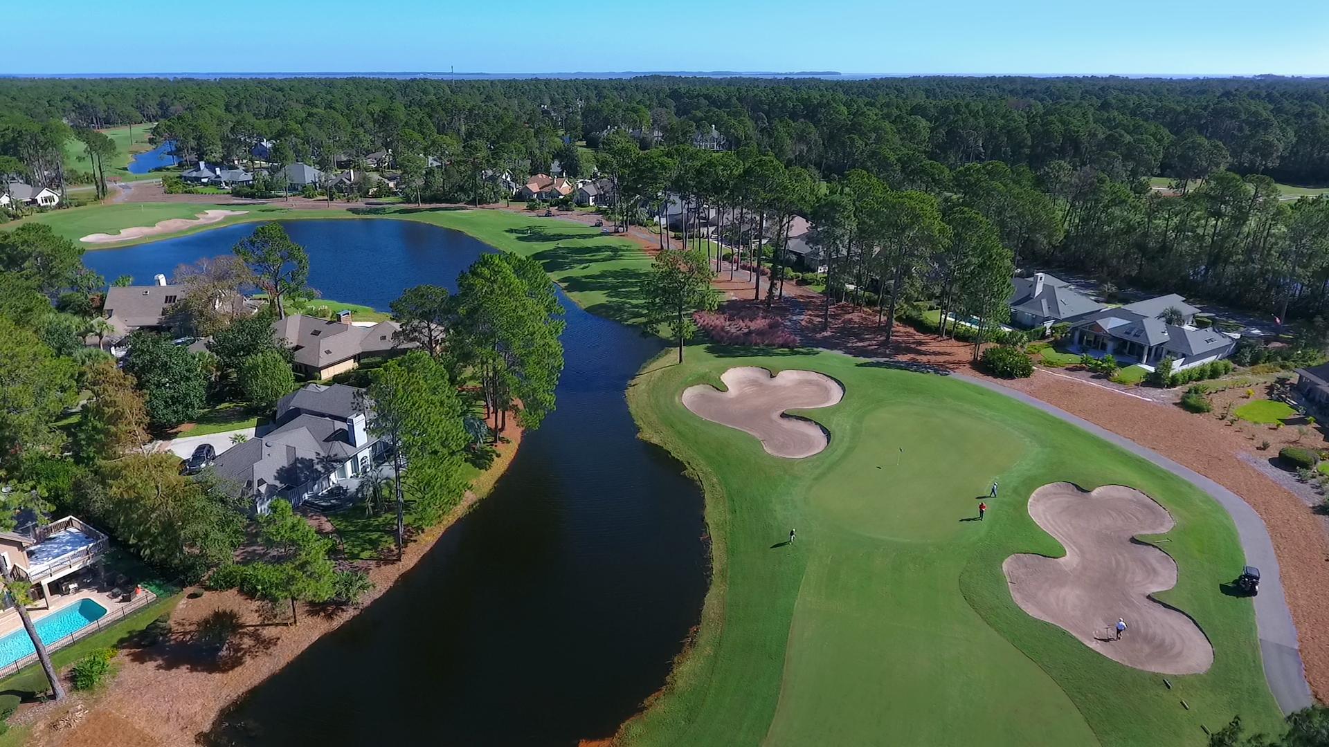 Aerial view of a golf course surrounded by homes and water features.