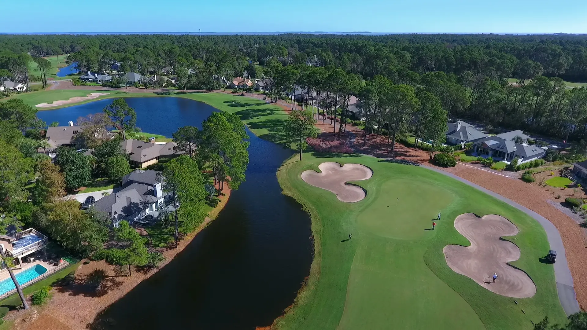 Aerial view of a golf course surrounded by homes and water features.