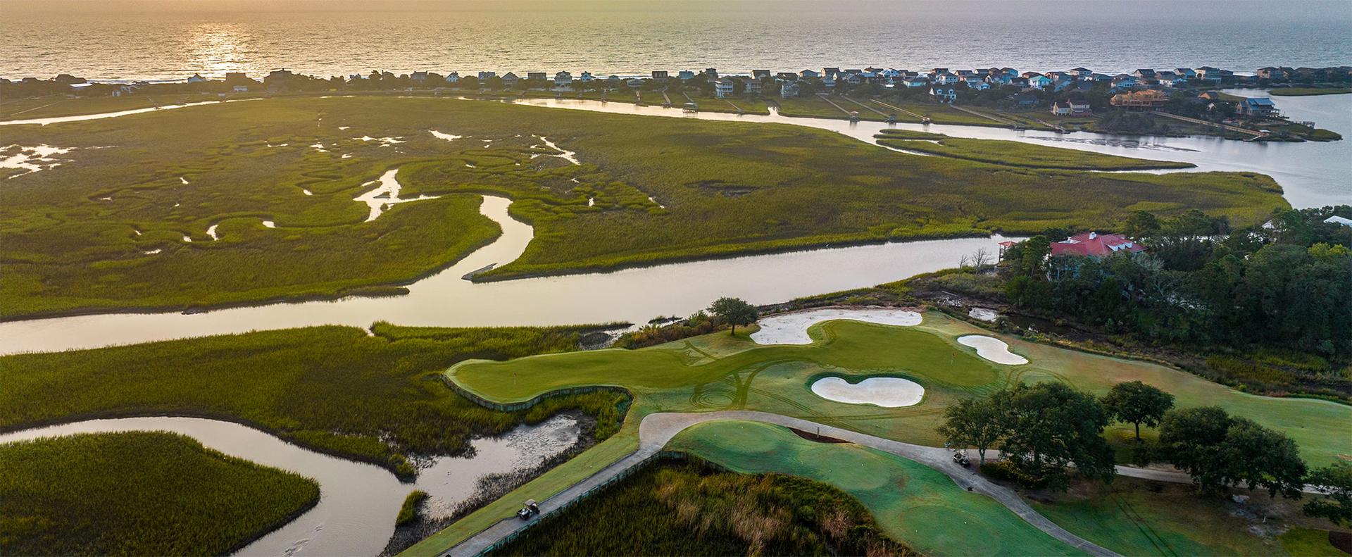 Birdseye view of a smooth green next to a sand bunker at sunset