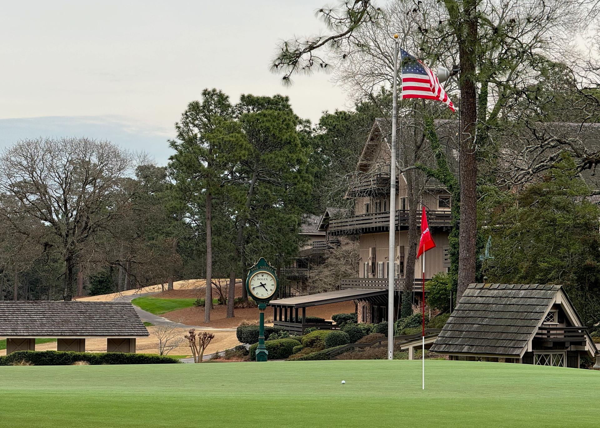 The Pine Needles clubhouse overlooking a smooth green featuring an american flag and a Rolex clock