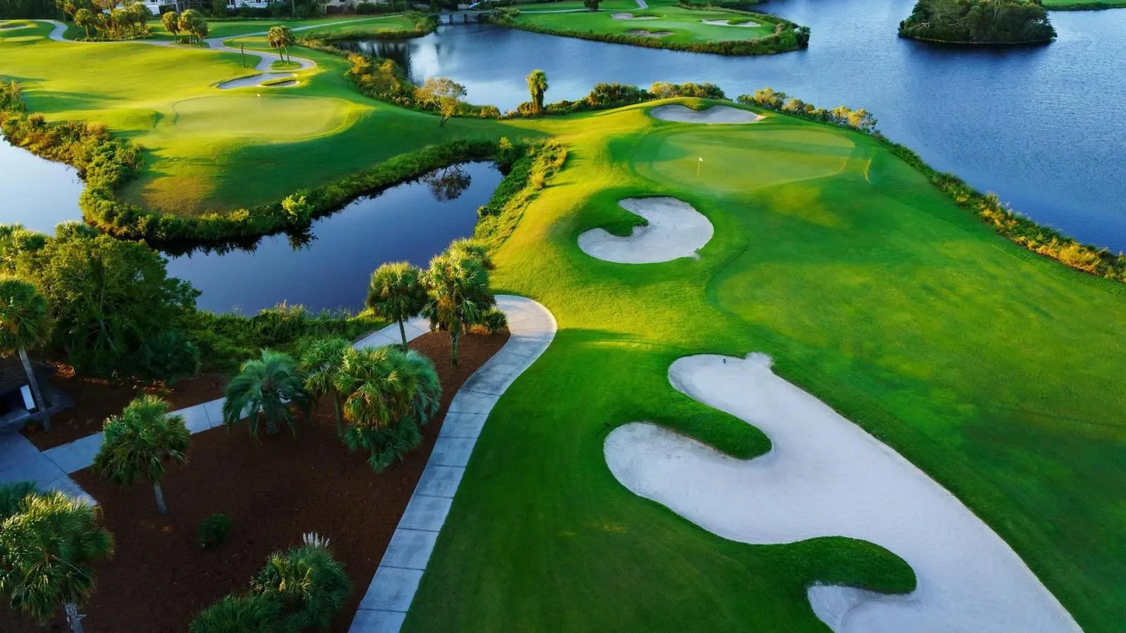 Overhead view a well maintained fairway leading to a smooth green surrounded by water hazards