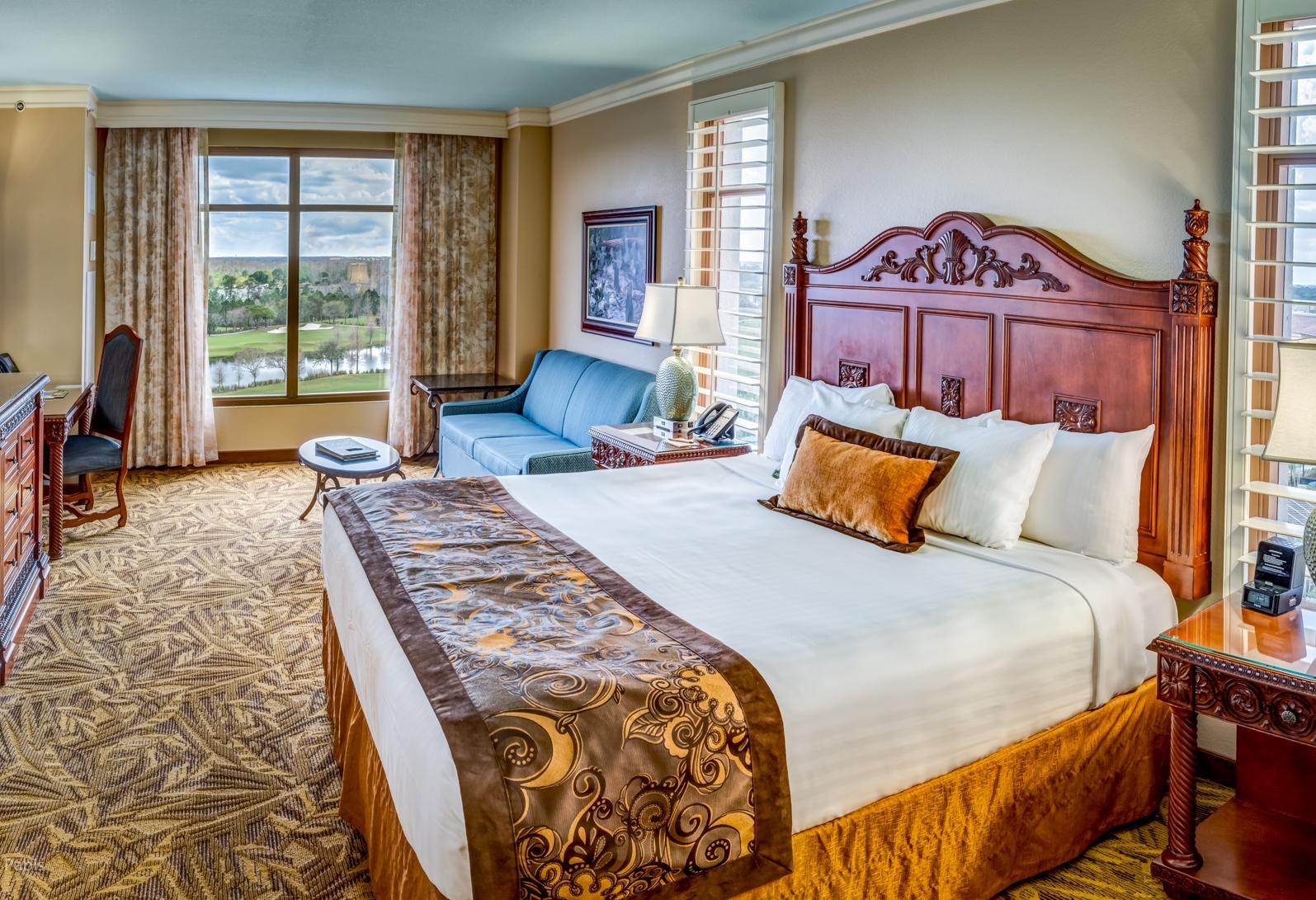 Spacious double bed suite at the Rosen Shingle Creek hotel with a sofa area and window views of the course
