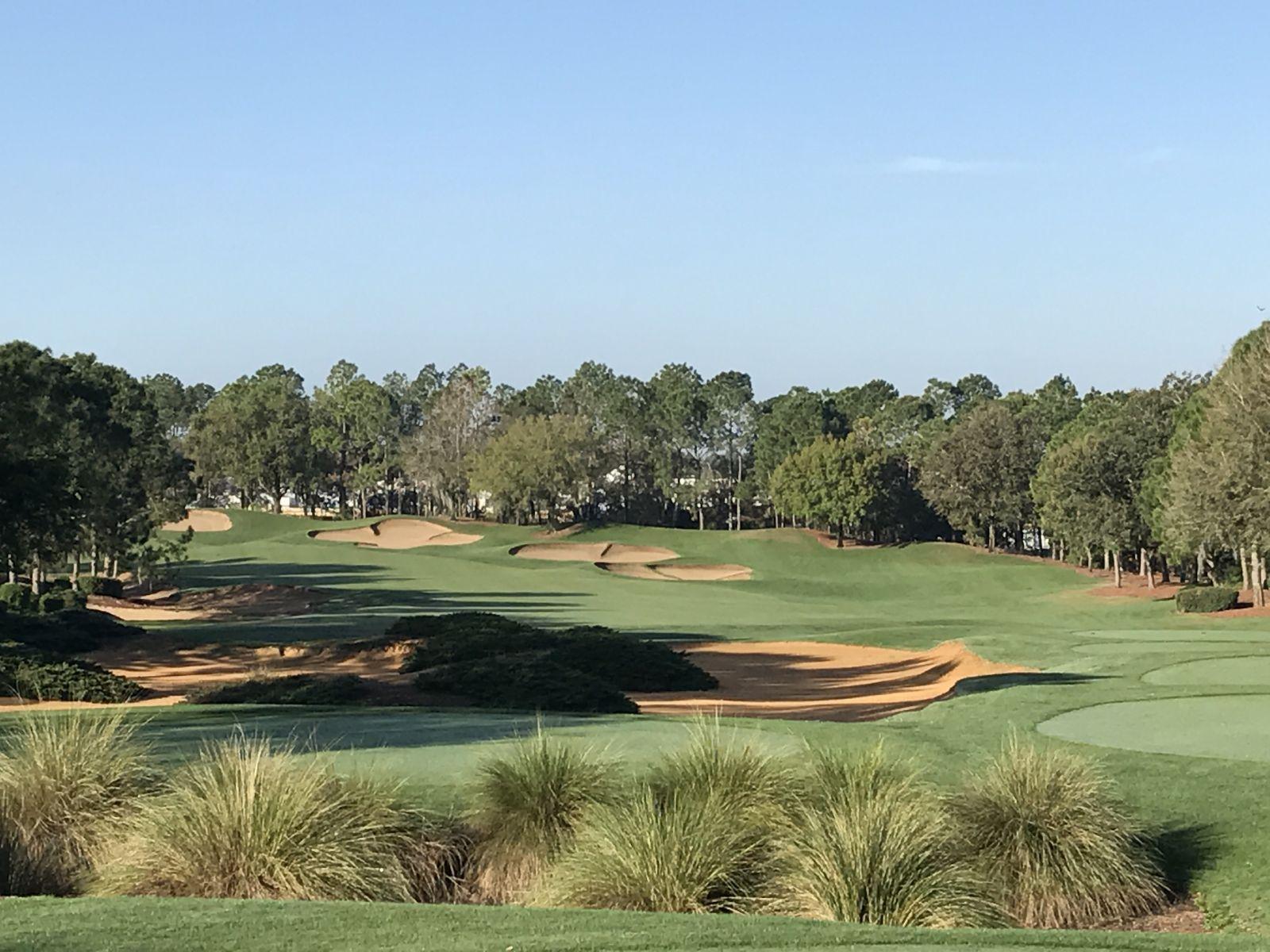 Fairway view showcasing a series of sand bunkers leading up to a green framed by trees.