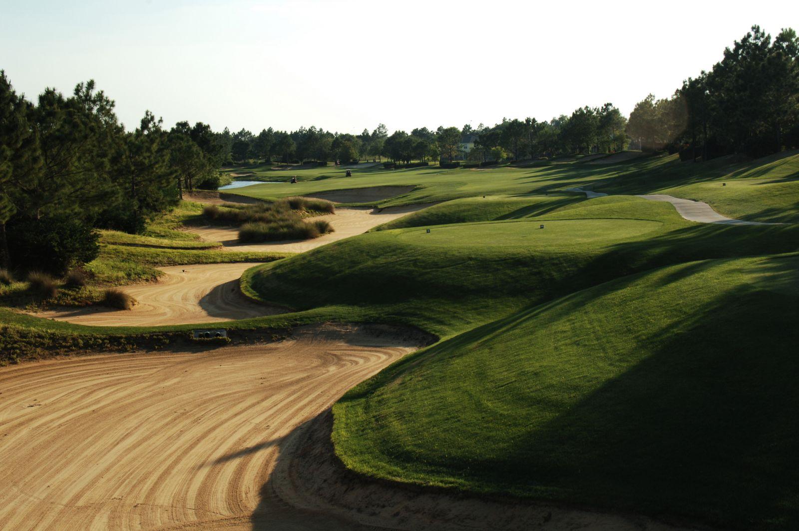 A dramatic fairway lined with sandy waste areas and rolling grassy mounds.