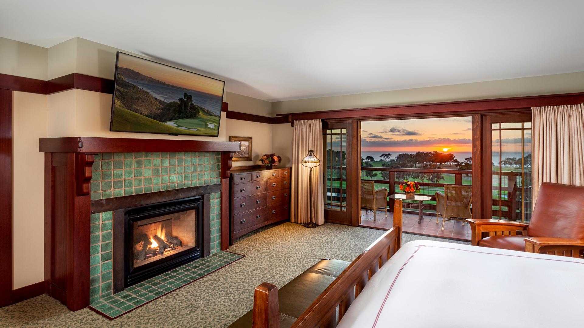 Double bed room at The Lodge with a large smart Tv and balcony views of the sun setting over the course