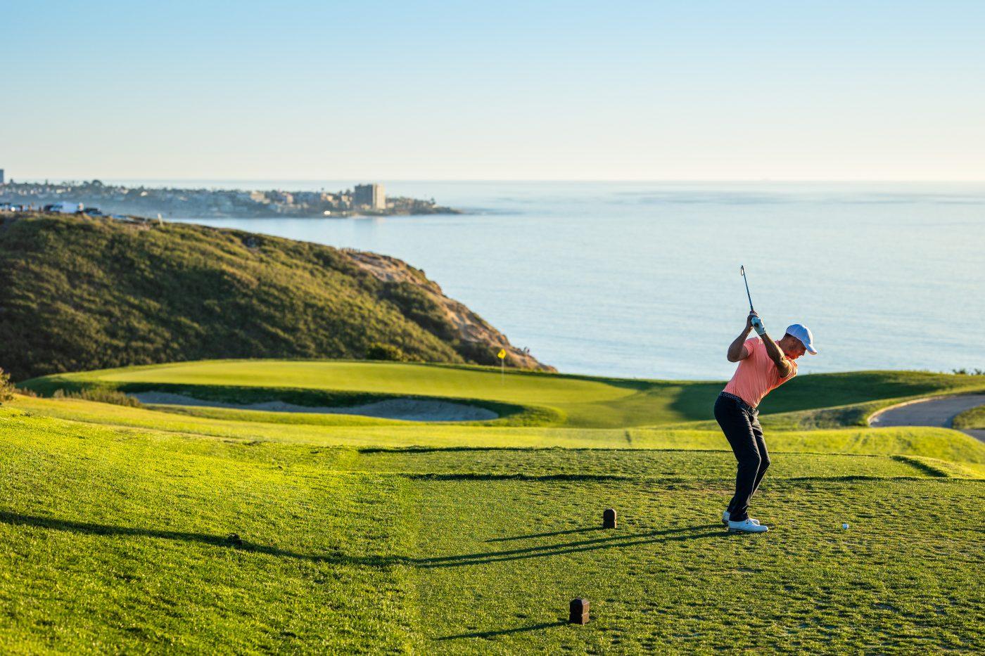 Golfer tee'ing off towards a smooth green at The Lodge Torrey Pines with sea views