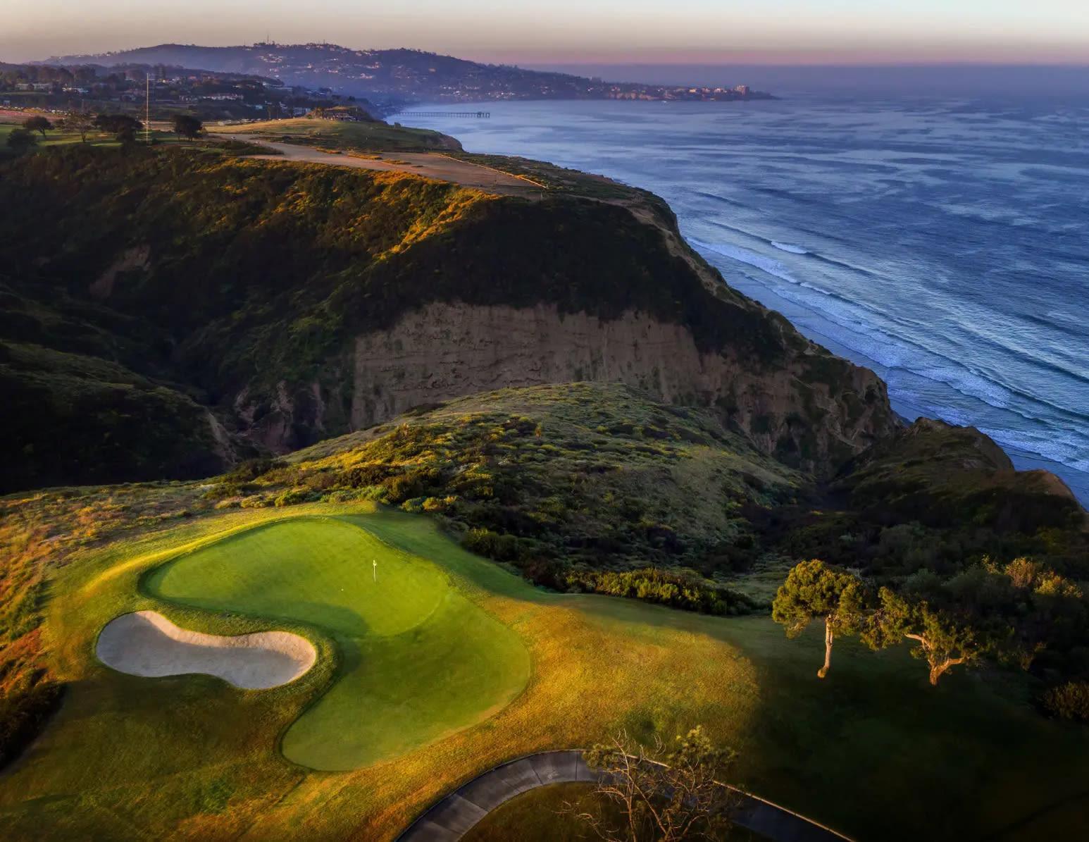 Aerial view of a well maintained green on the course with coastal views