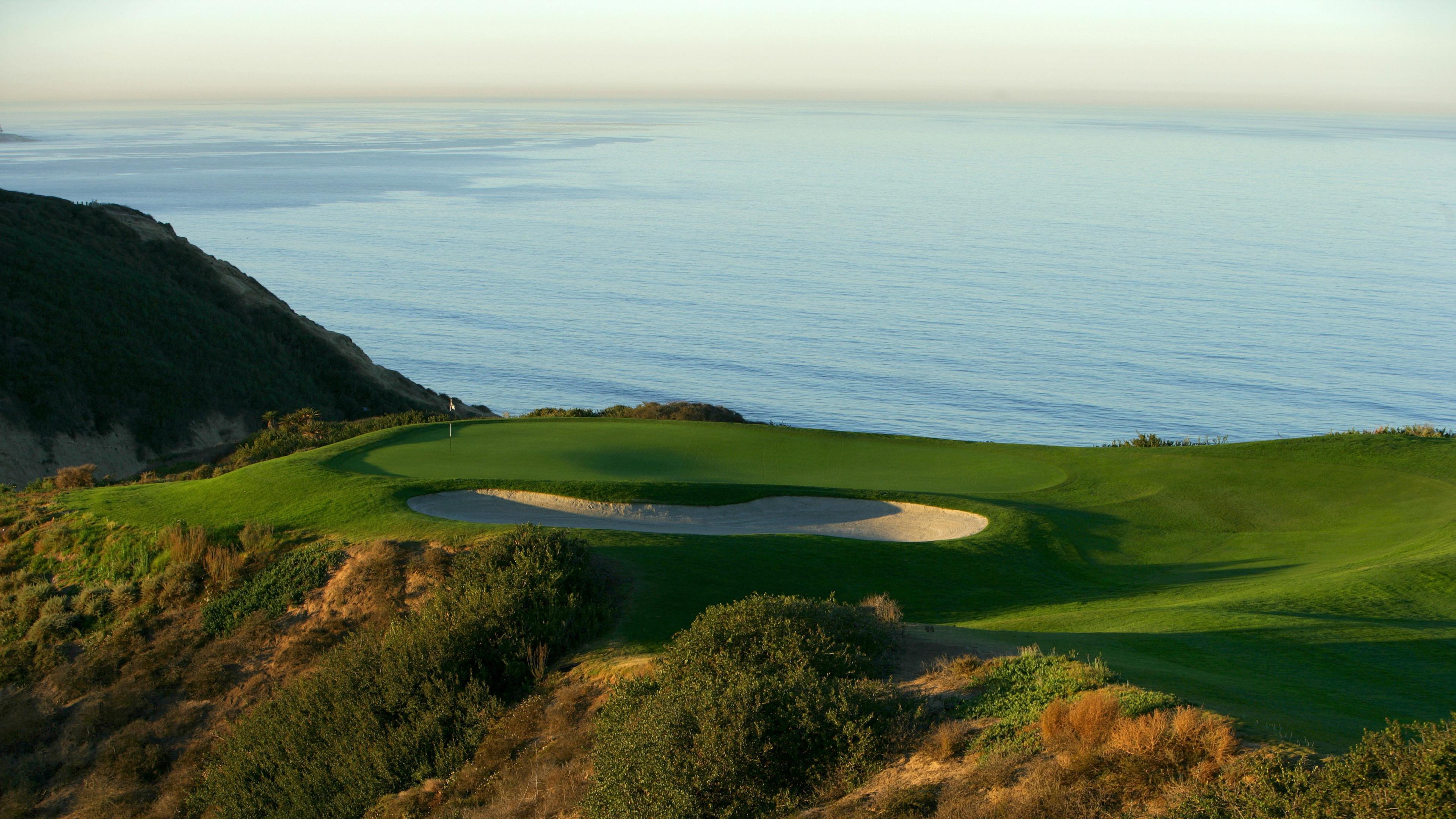 A smooth green at the Torrey Pines South Course placed next to a sand bunker with sea views