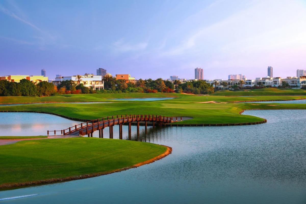 An island green surrounded by water with a bridge to navigate the Address Montgomerie Golf Course