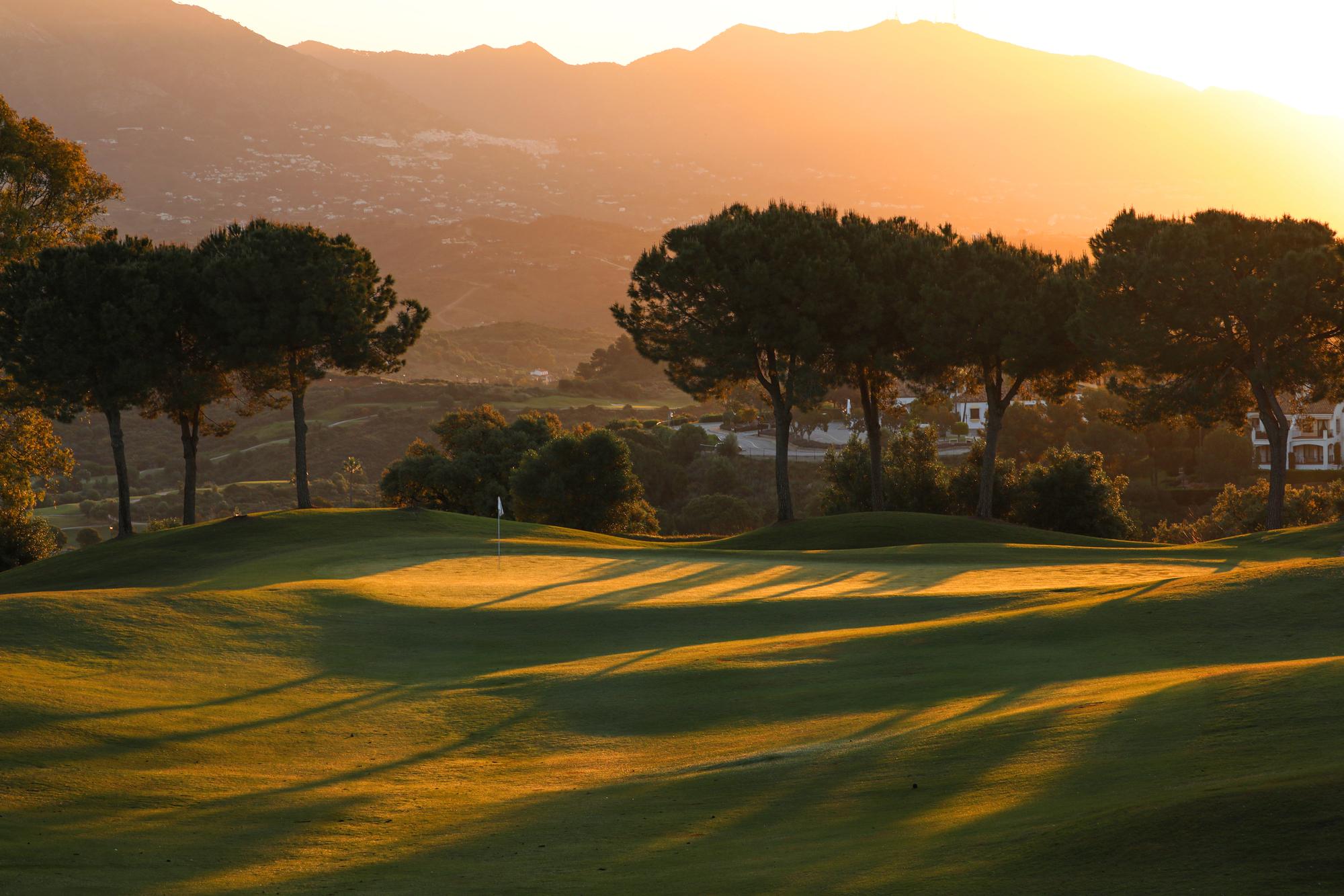View of a green at dusk with mountains in the background