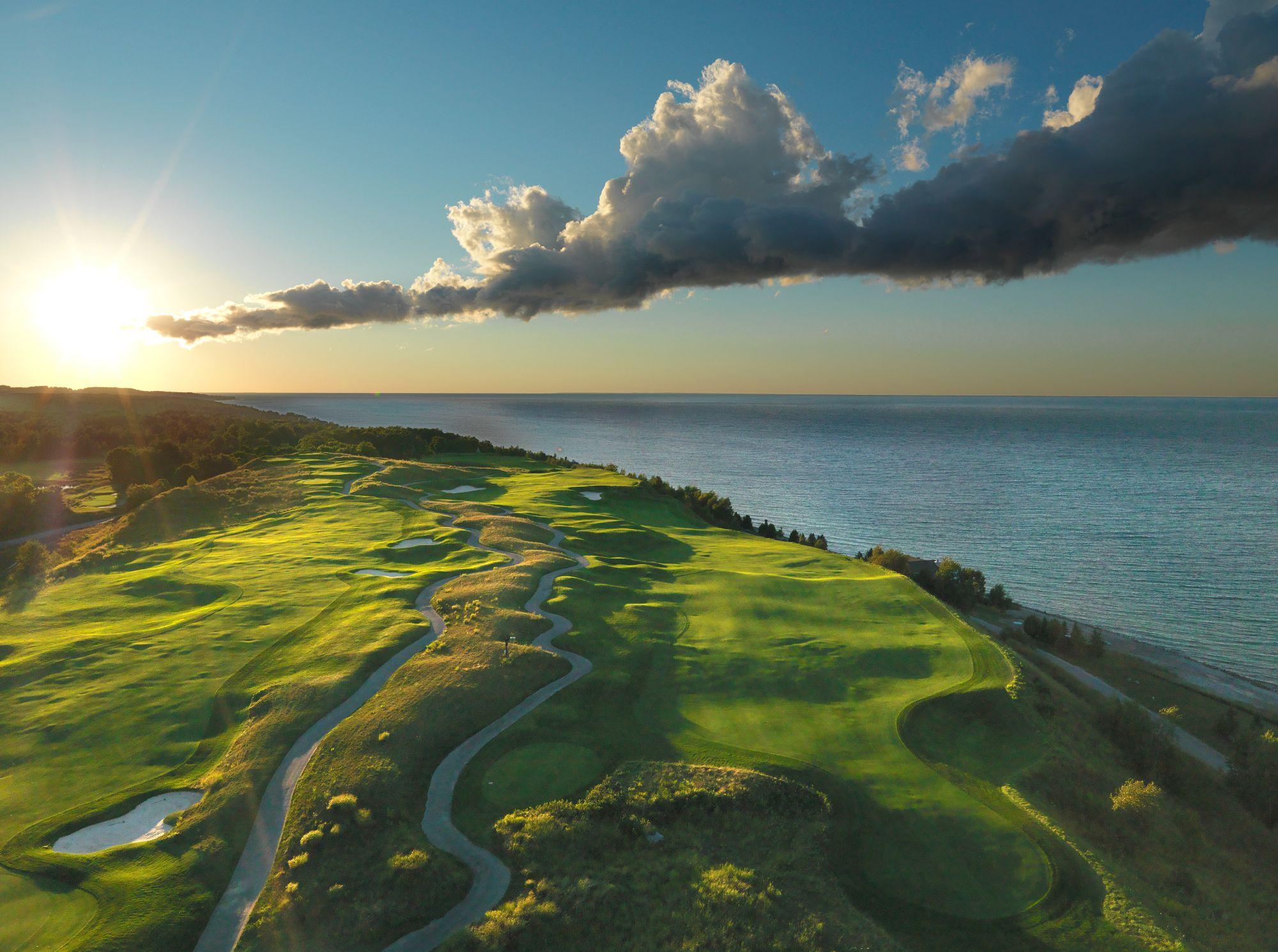 Stunning lakefront golf course with rolling fairways illuminated by a vibrant sunrise.