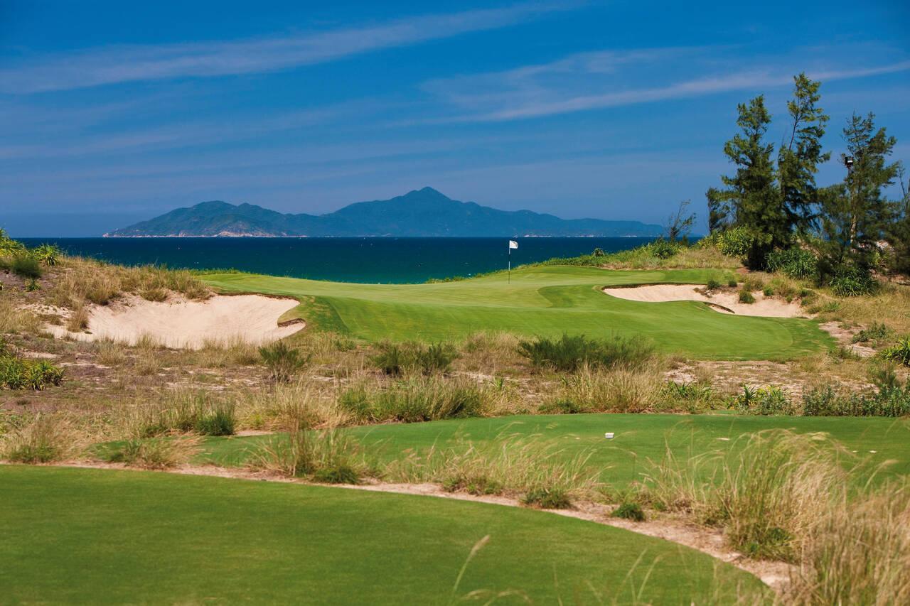 A smooth green with coastal views next to rolling dunes and a strategically placed sand bunker