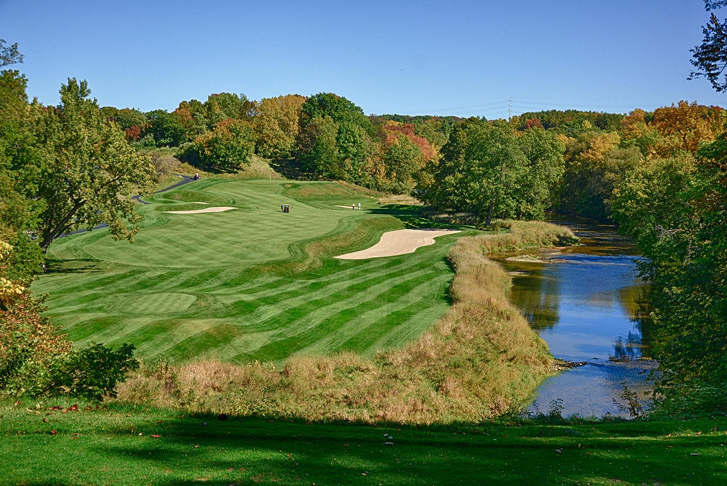 Blackwolf Run golf course’s fairway winding along a scenic river with vibrant autumn foliage.