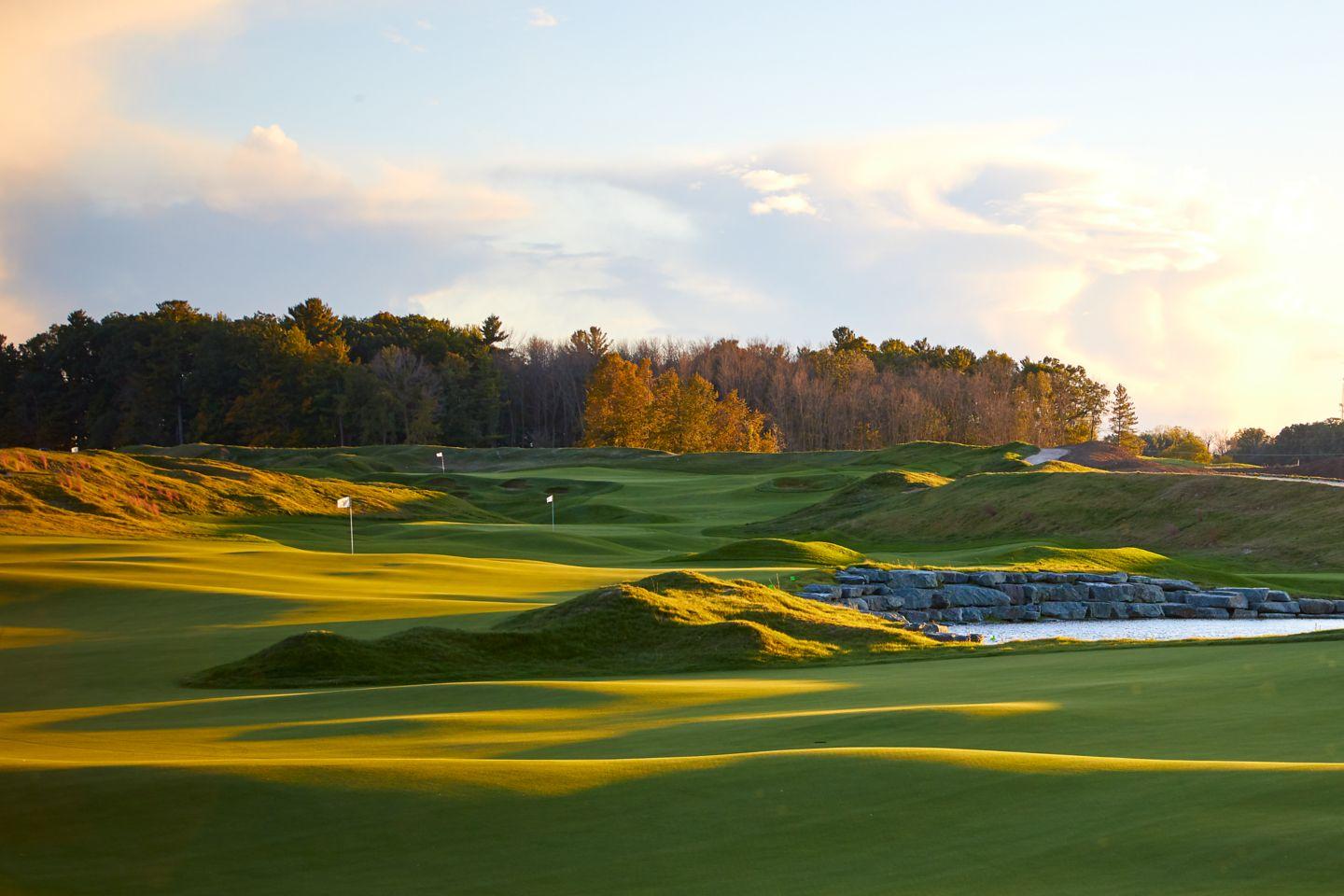 Rolling greens and water features on a world-class golf course at sunset.