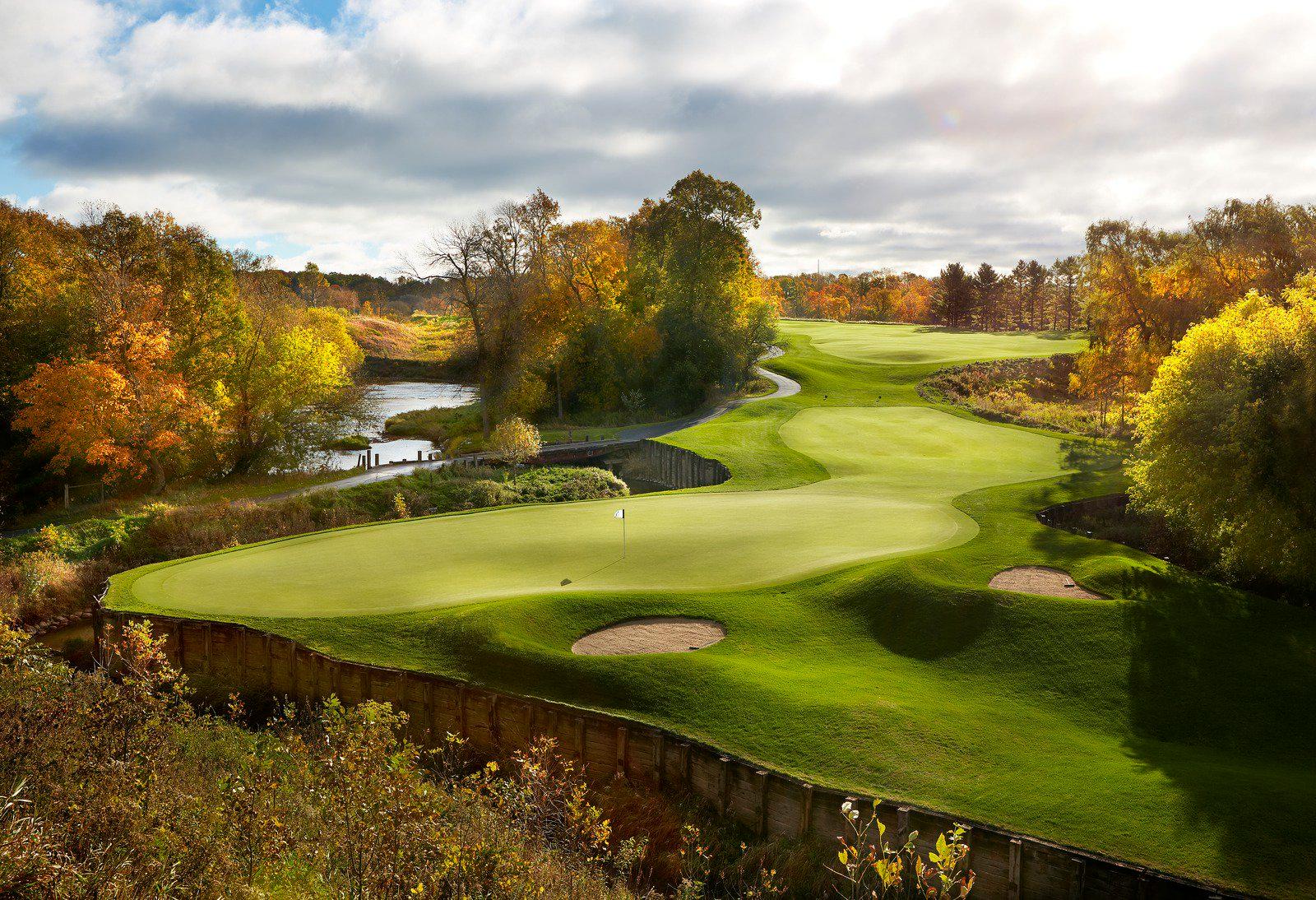 Elevated green overlooking a winding fairway surrounded by colorful fall trees.