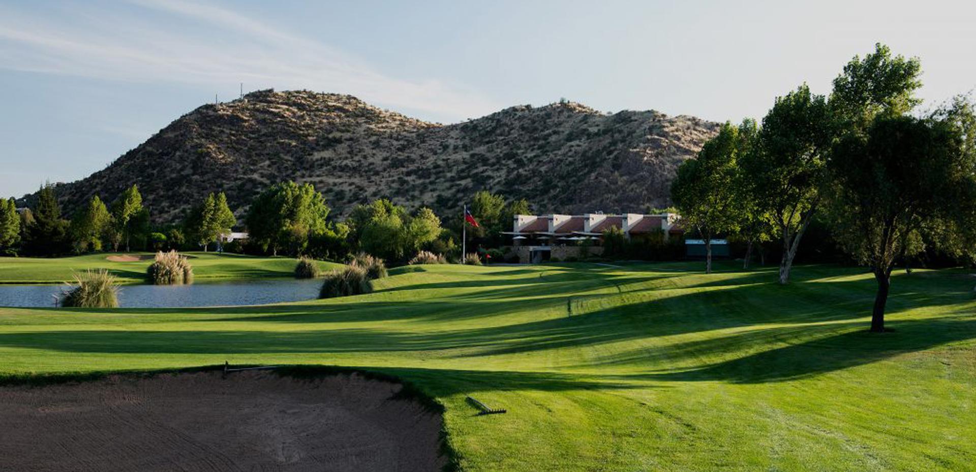 Lush fairway leading toward the clubhouse with hills in the background