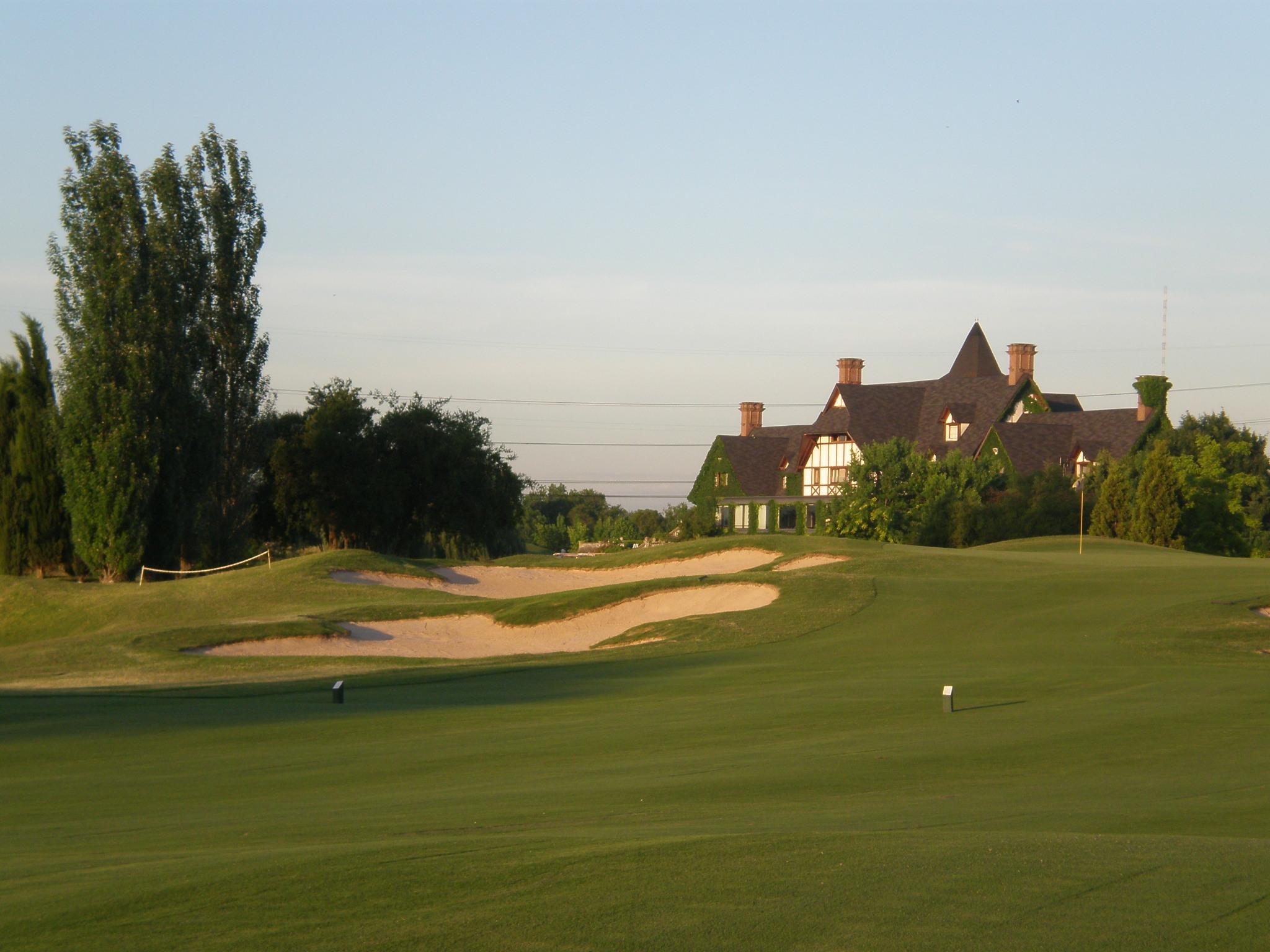 Manicured fairway leading to a green with the clubhouse in the background