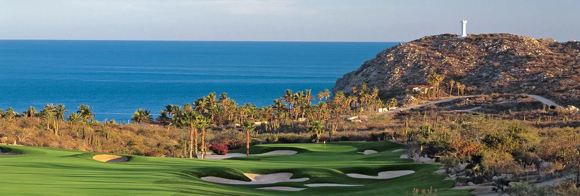 Panoramic view of a green littered with sand bunkers and lovely sea views