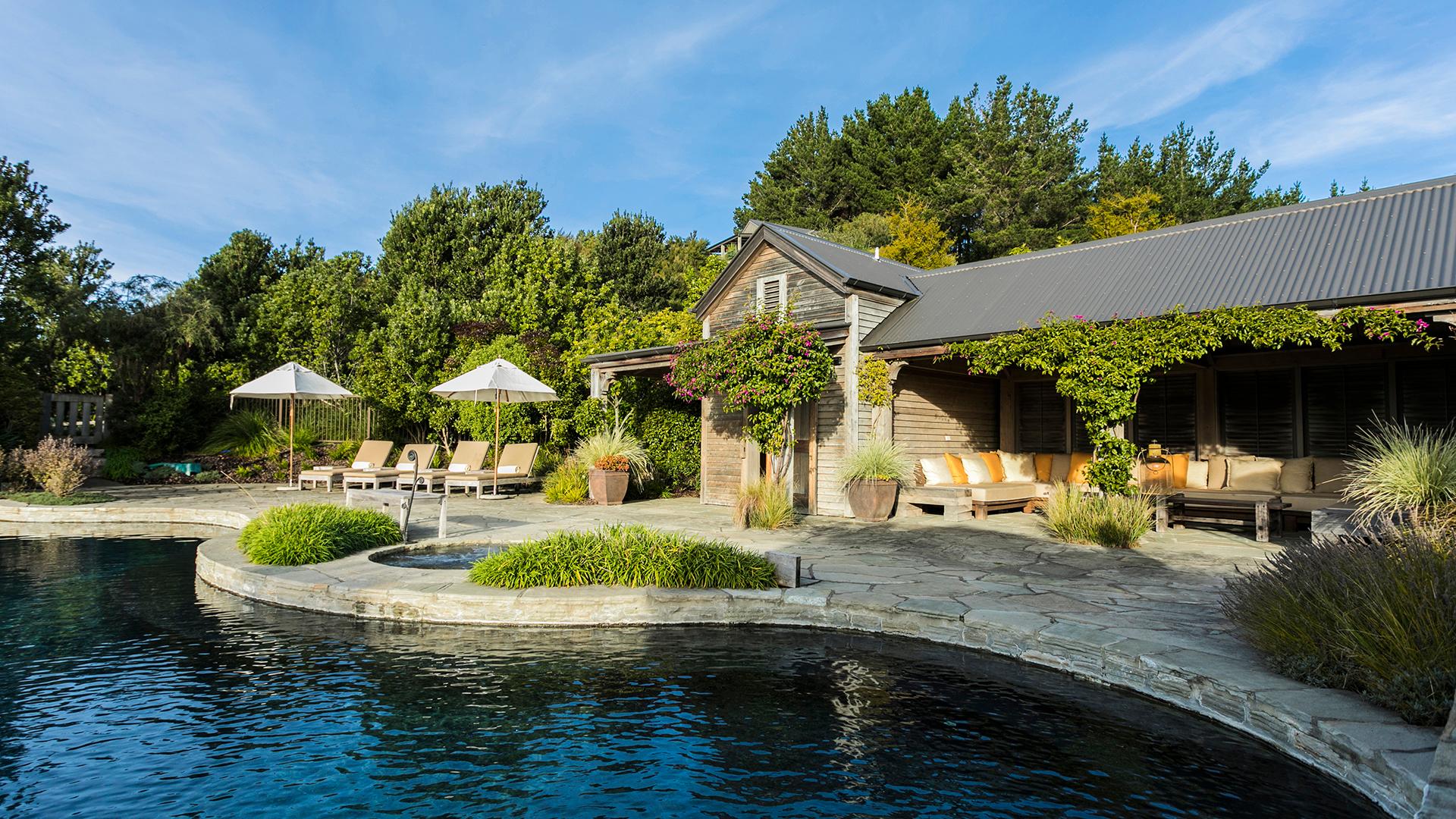 The Cape Kidnappers Resort clubhouse with an outdoor swimming pool nestled with sunbeds