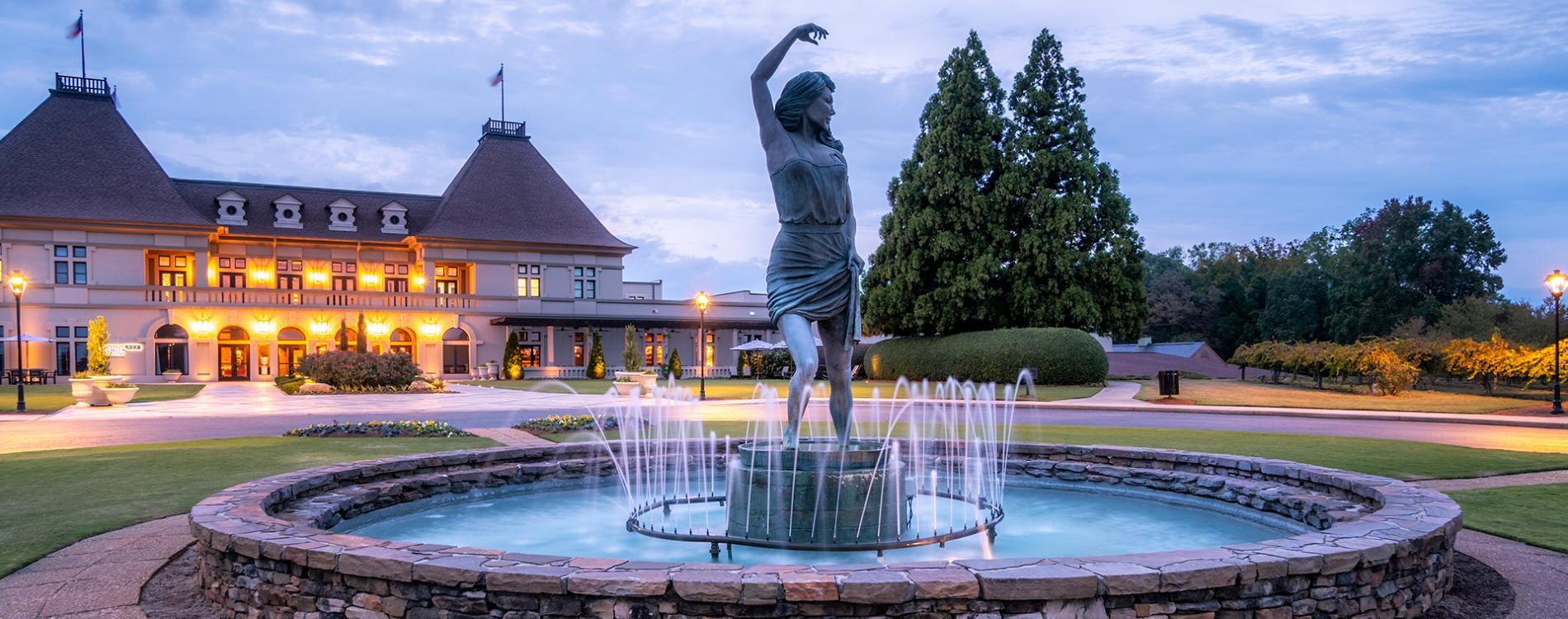 A grand entrance at Chateau Elan features a glowing fountain centerpiece surrounded by manicured grounds and elegant lighting.