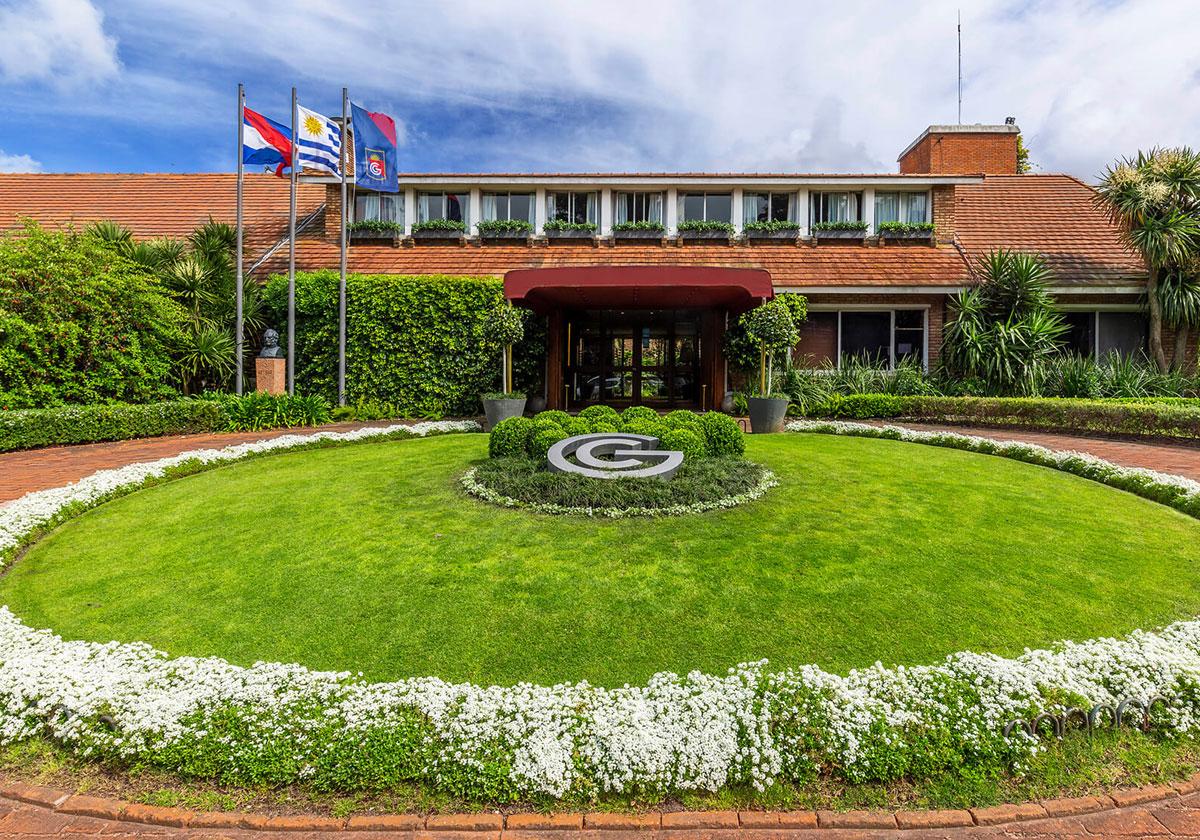 The main entrance of a golf club with flags and a well-maintained circular garden
