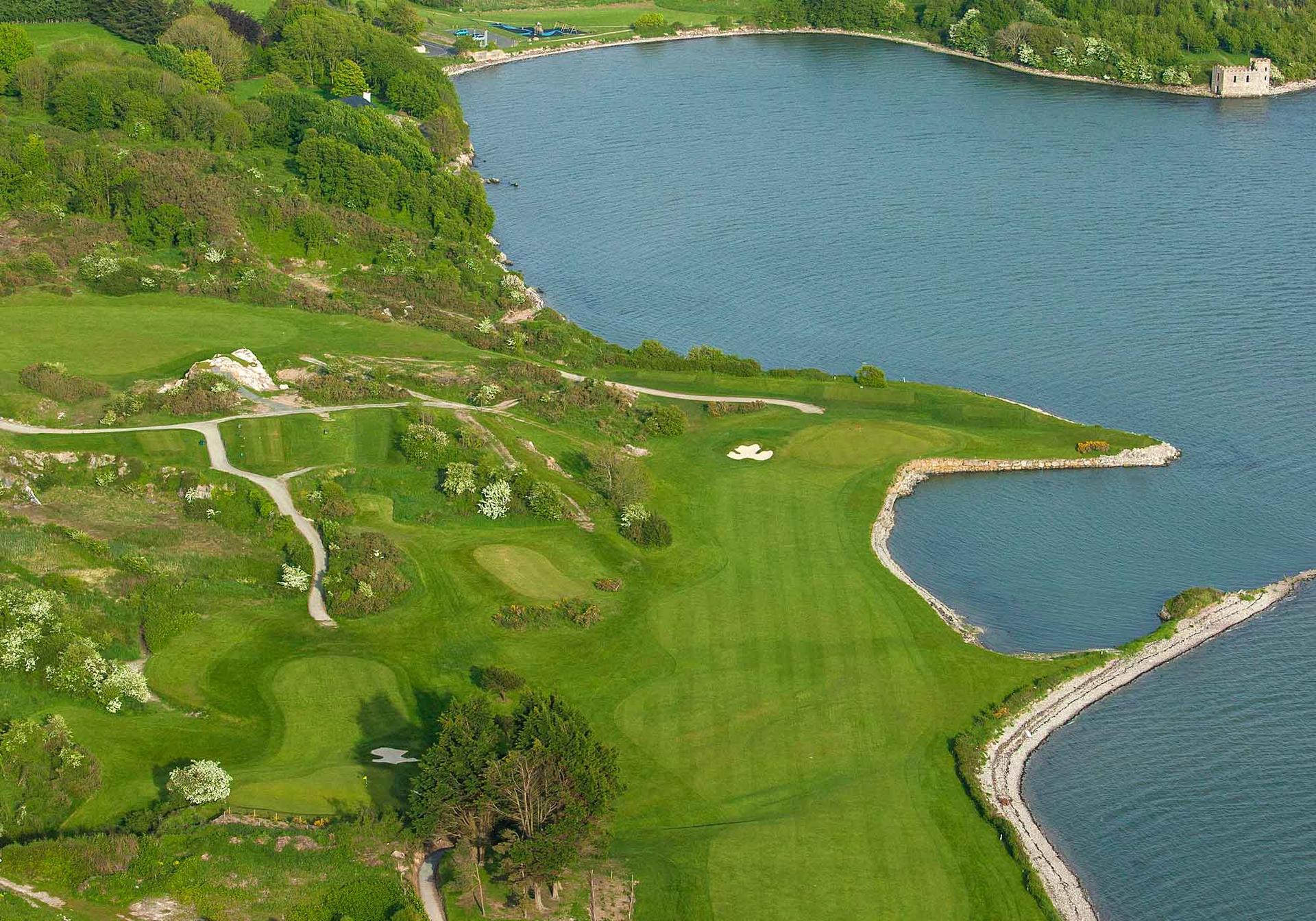 Aerial view of Cork Golf Club’s dramatic coastline holes set against sparkling blue waters.