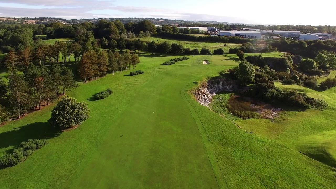 A tree-lined fairway weaving through natural rock formations and challenging bunkers.