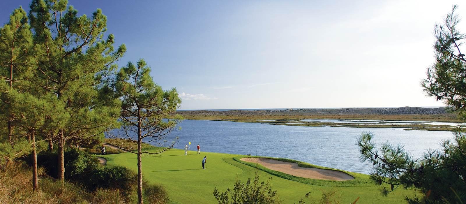 Three players on the green with water behind