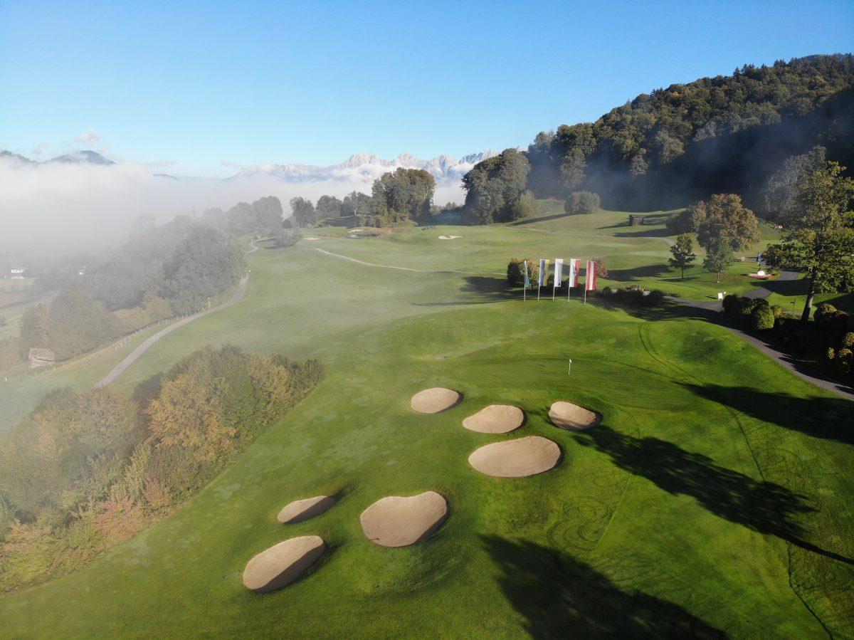 Aerial view of a smooth green littered with sand bunkers on a foggy day