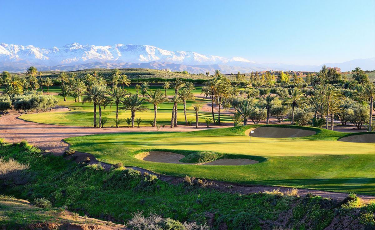 A well maintained green surrounded by sand bunkers with mountain views