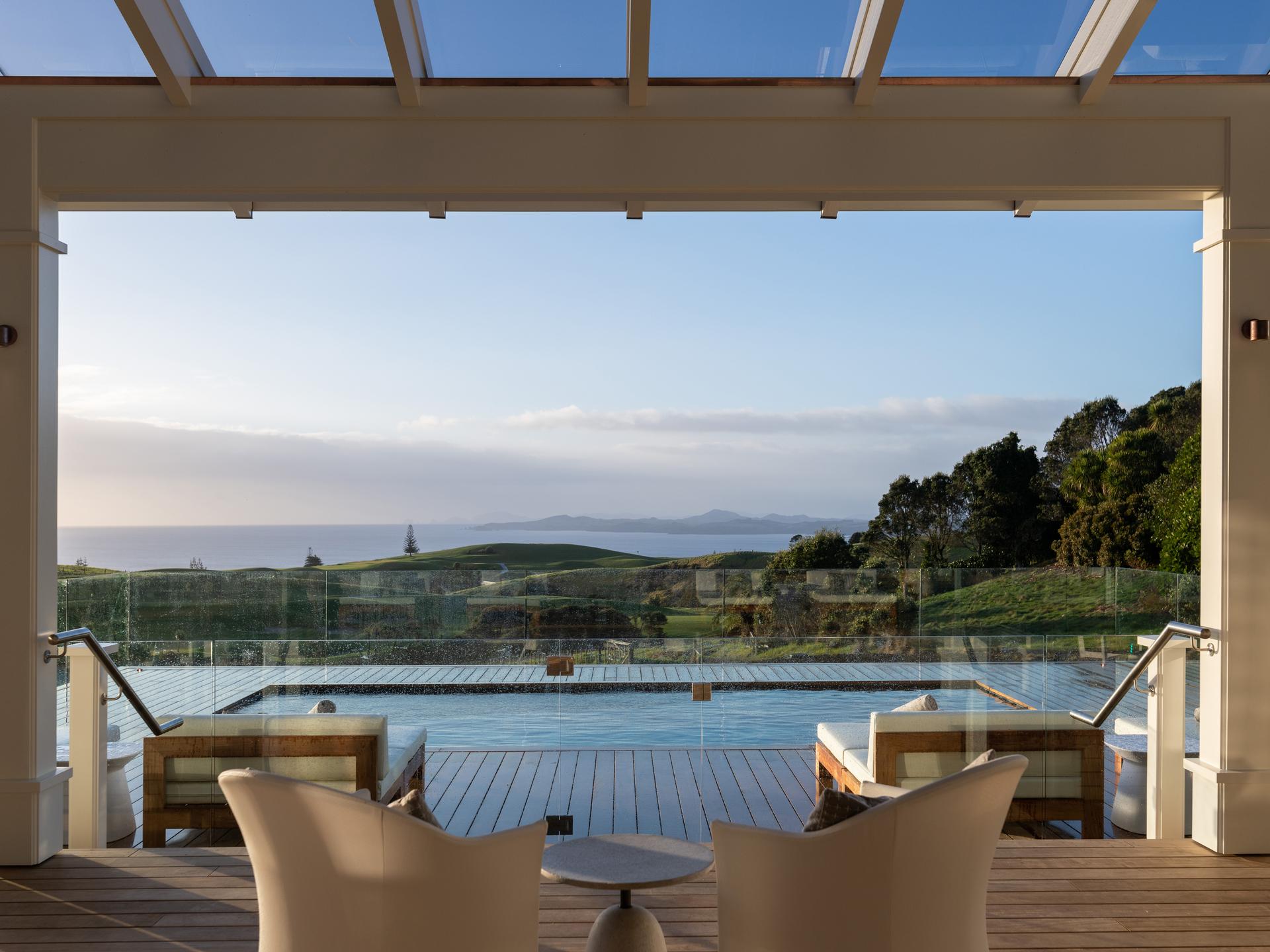 An outdoor swimming pool at the resort with coastal views in the distance