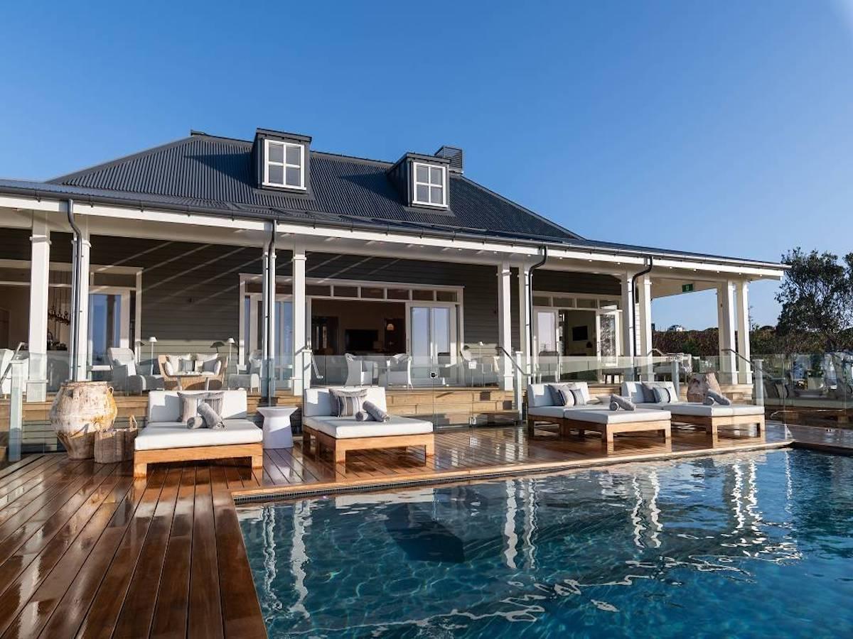 The Kauri Cliffs Resort clubhouse with an outdoor swimming pool surrounded by sand bunkers