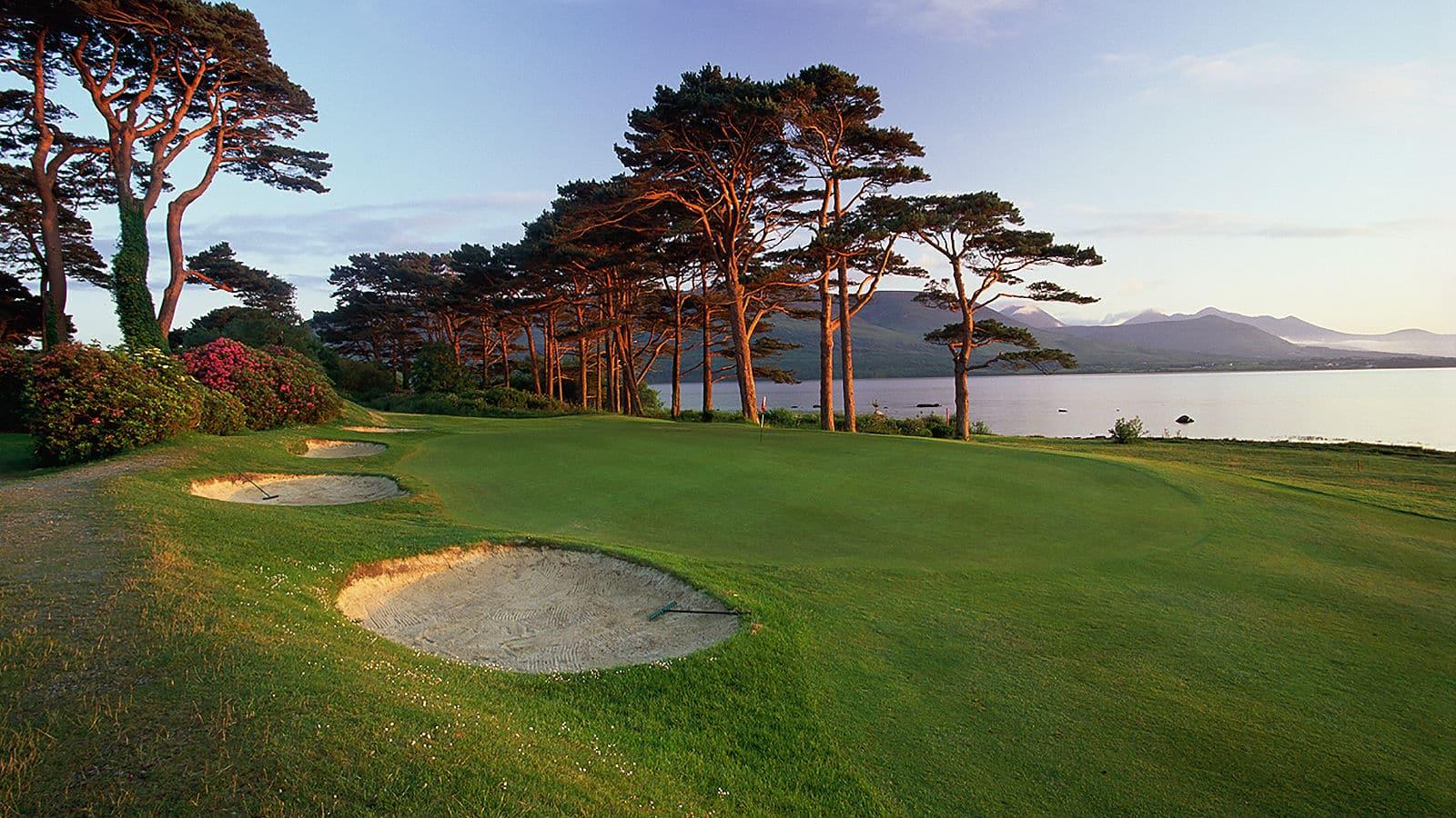 A scenic green framed by sand bunkers and overlooking the lake.