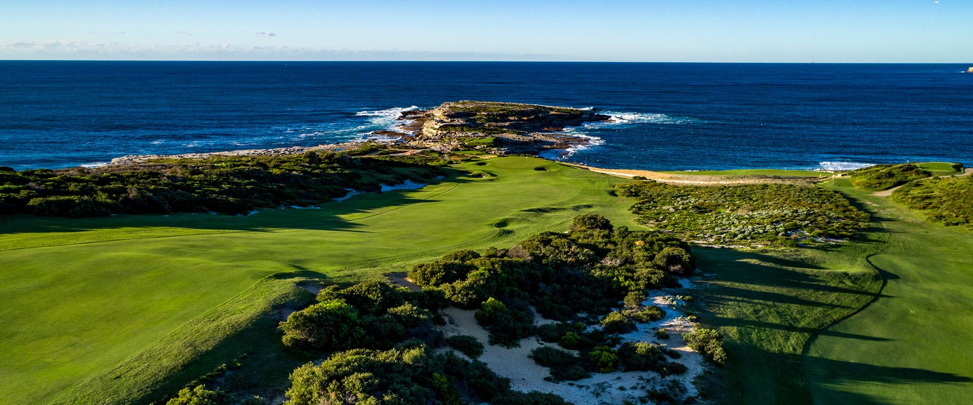 Overhead view of a wide fairway leading to a smooth green just before the coast