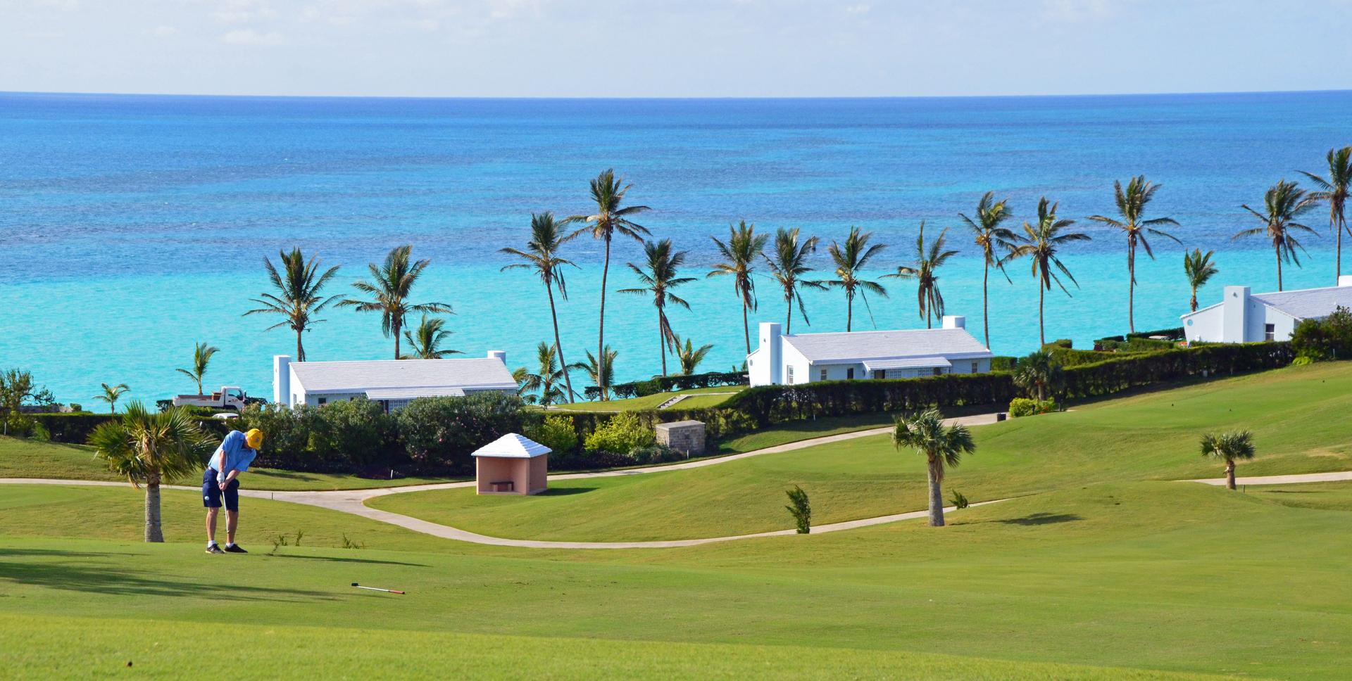Gentleman playing his round of golf with sea views framed by palm trees